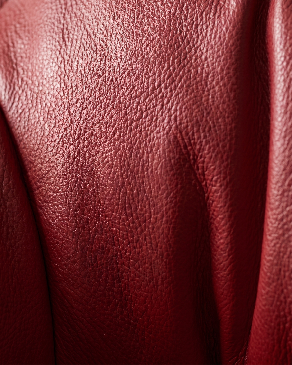 Close-up of textured red leather upholstery with visible grain and stitched seams.