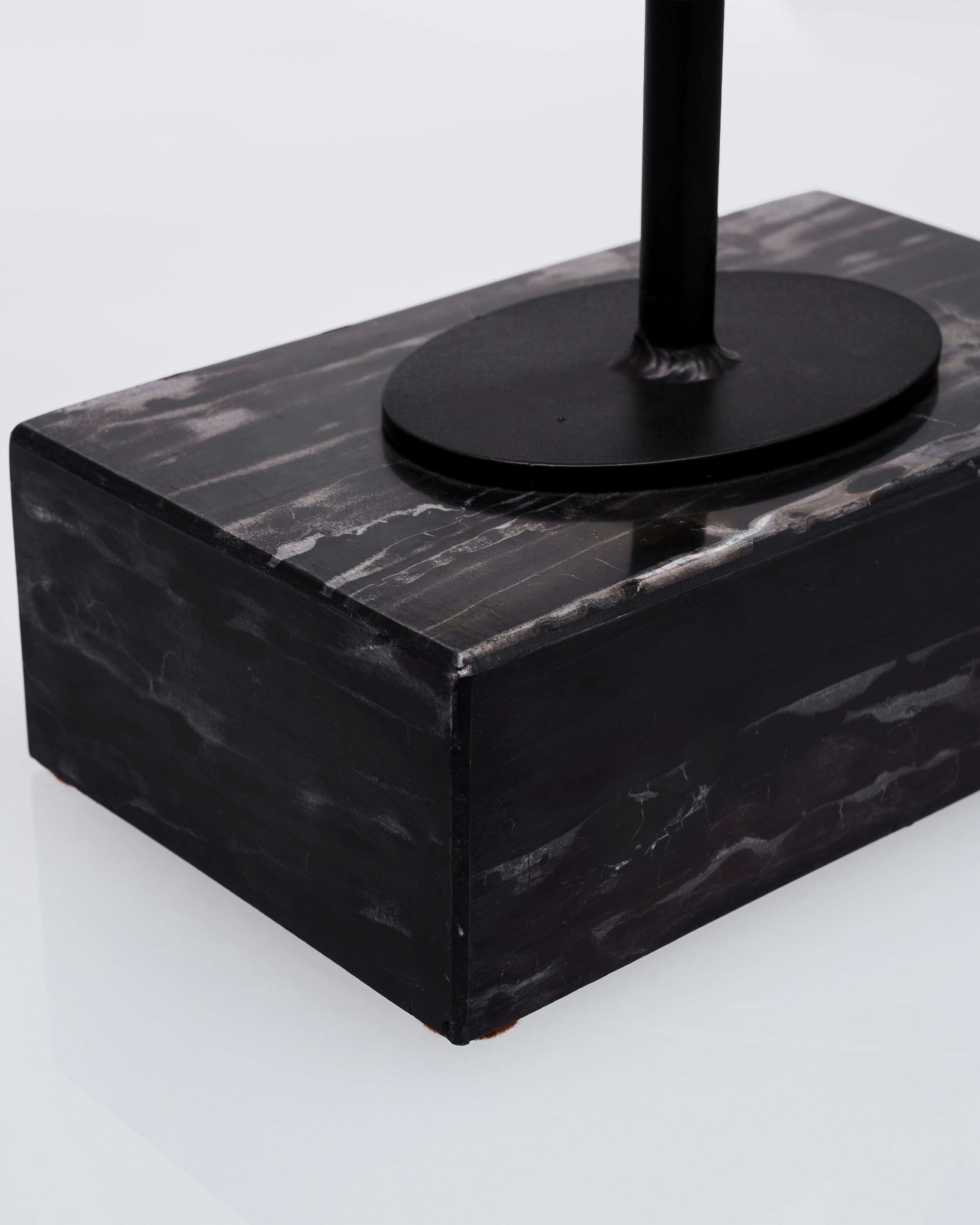Black marble base with a black cylindrical object on a white background