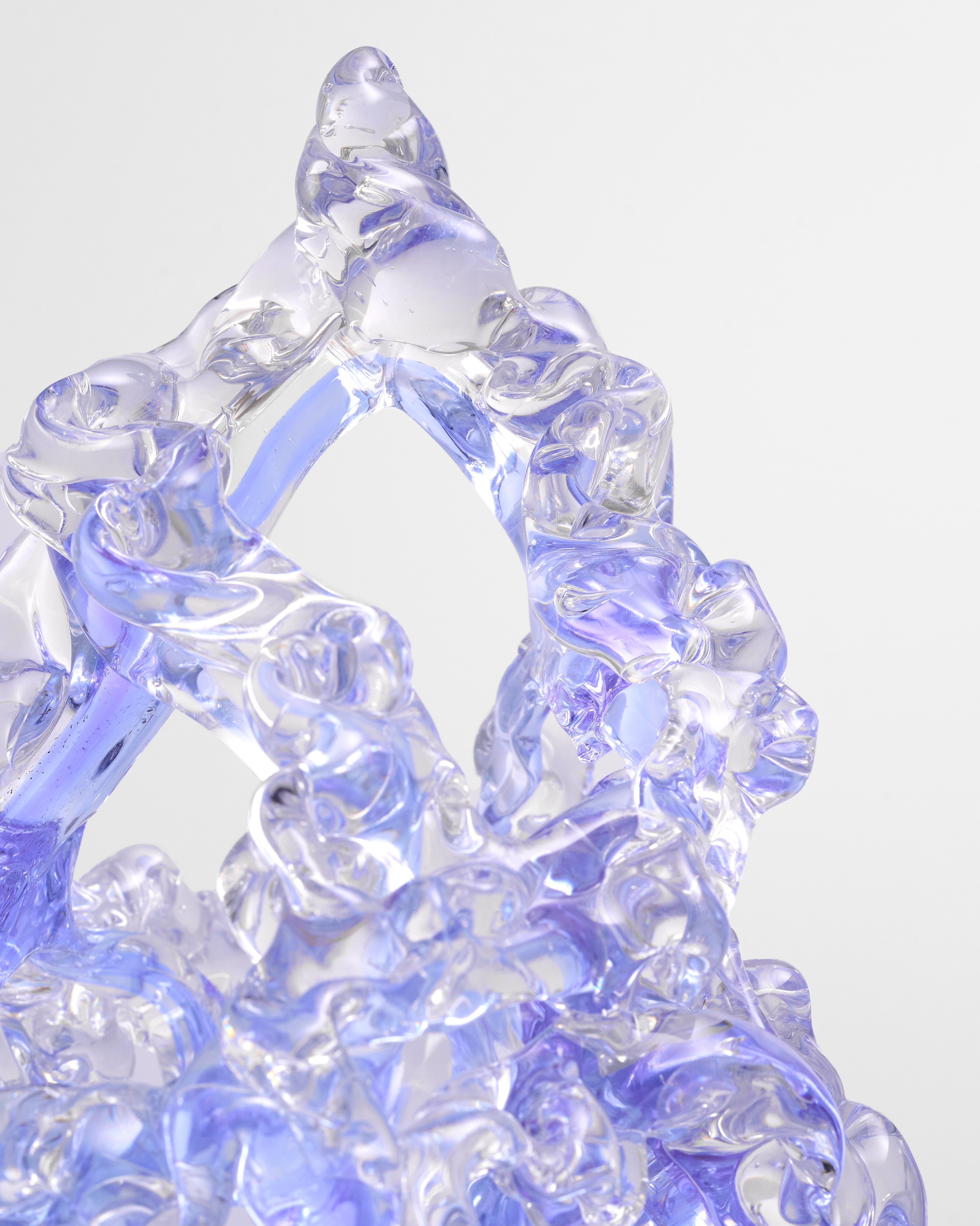 Clear glass sculpture with blue tint on a white background