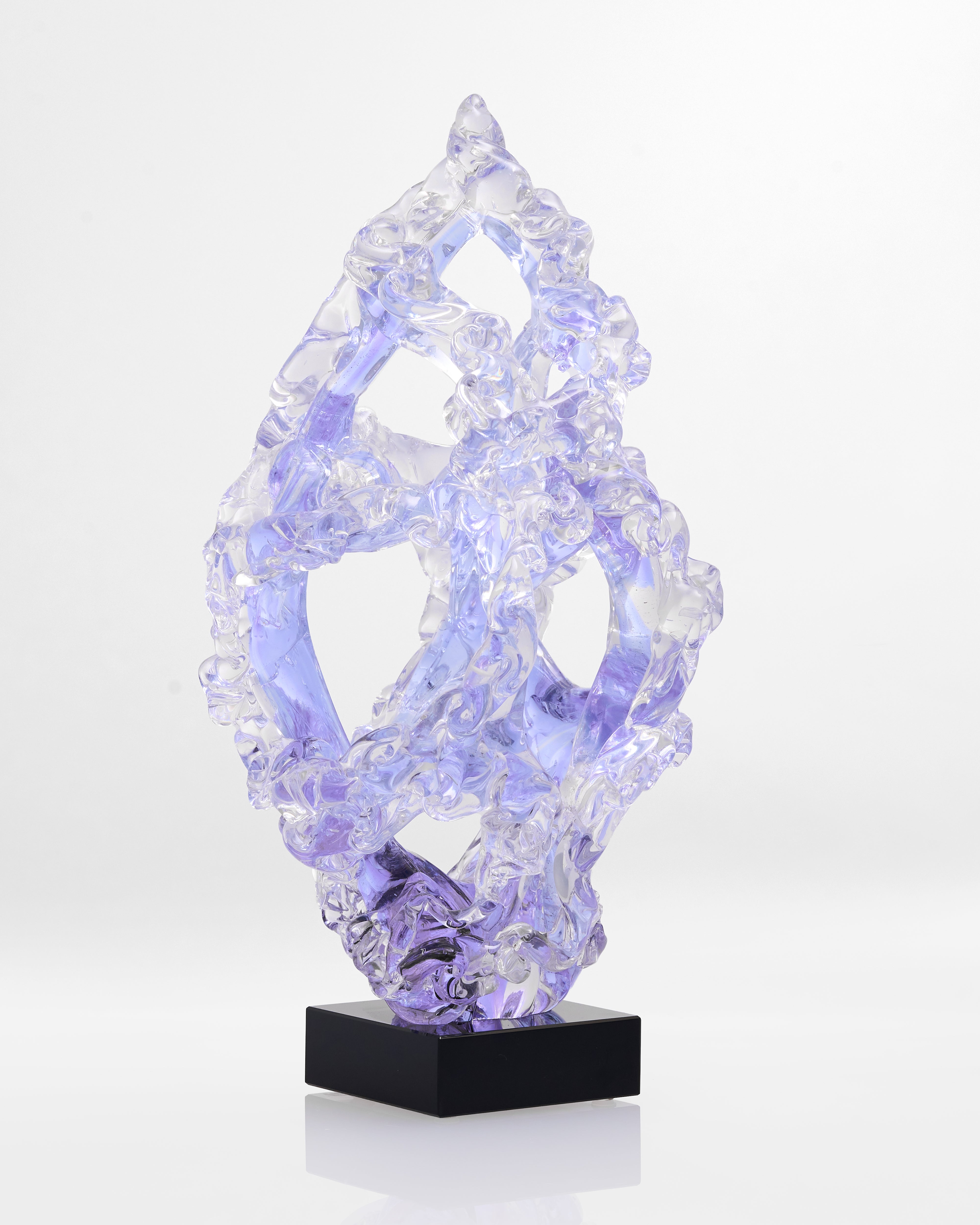 Crystal-like sculpture on a black base against a white background