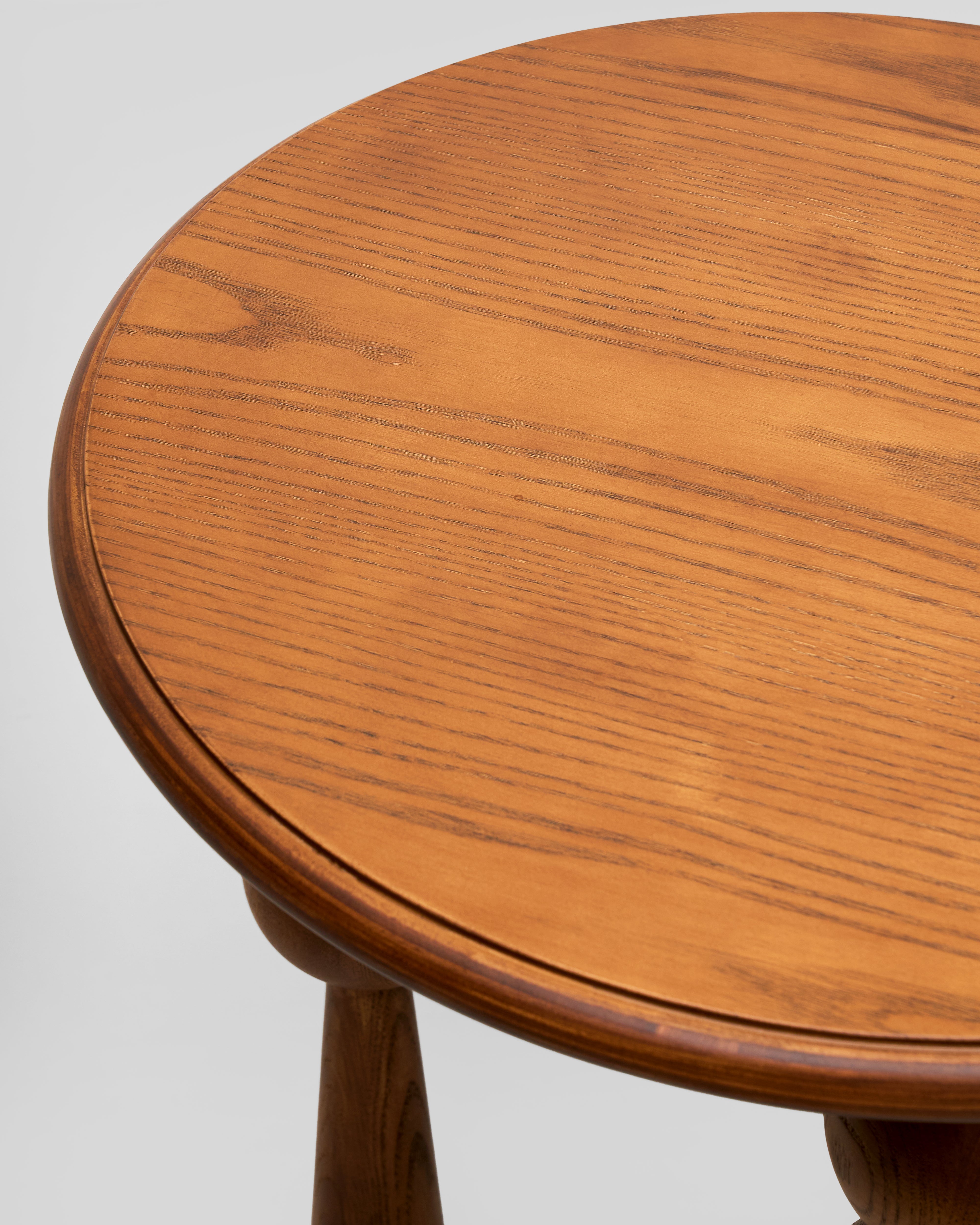 Wooden round table with a light brown finish on a white background