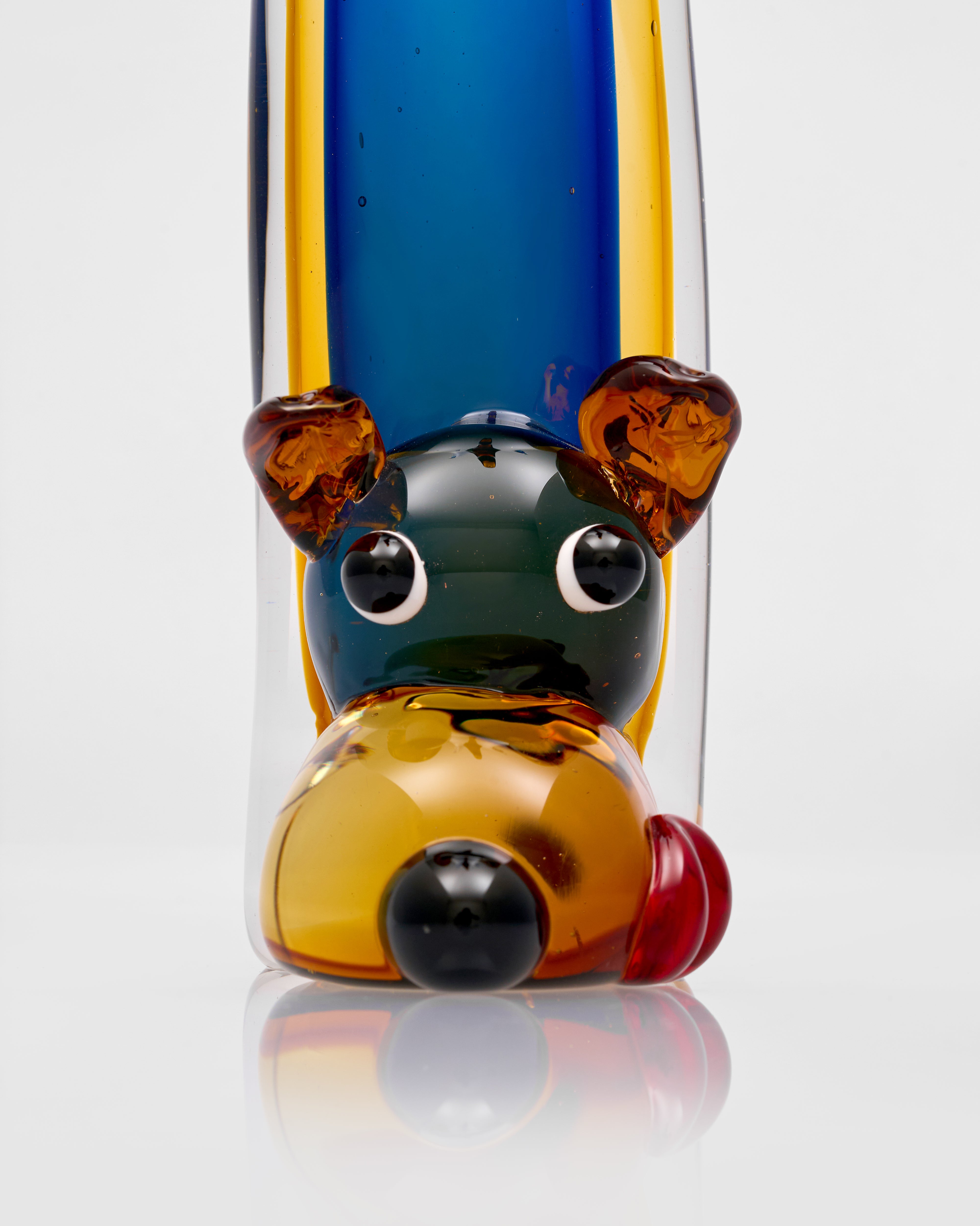 Colorful glass bear figure with a blue, yellow, and amber design on a white background