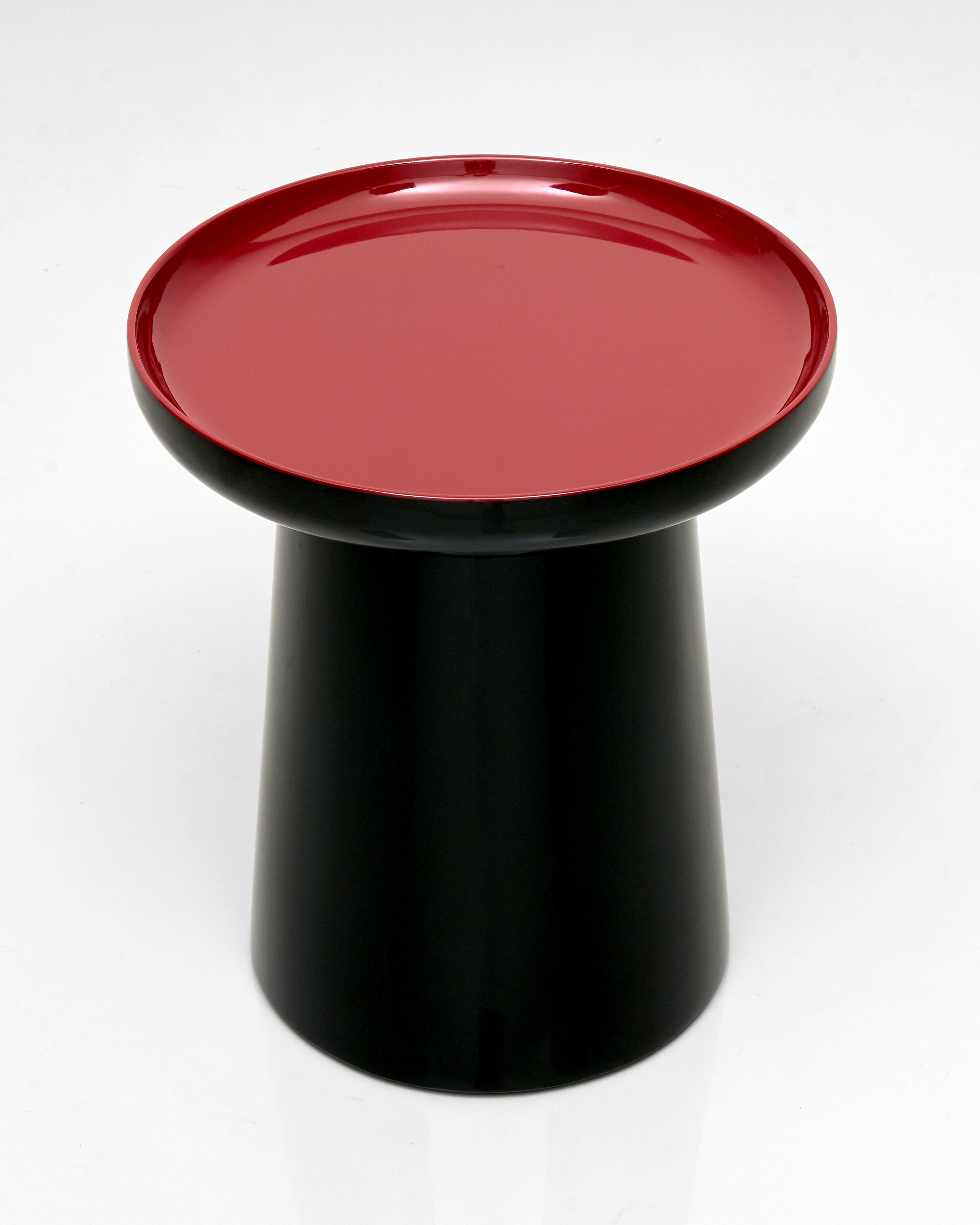 Black cylindrical stool with a red circular seat on a white background