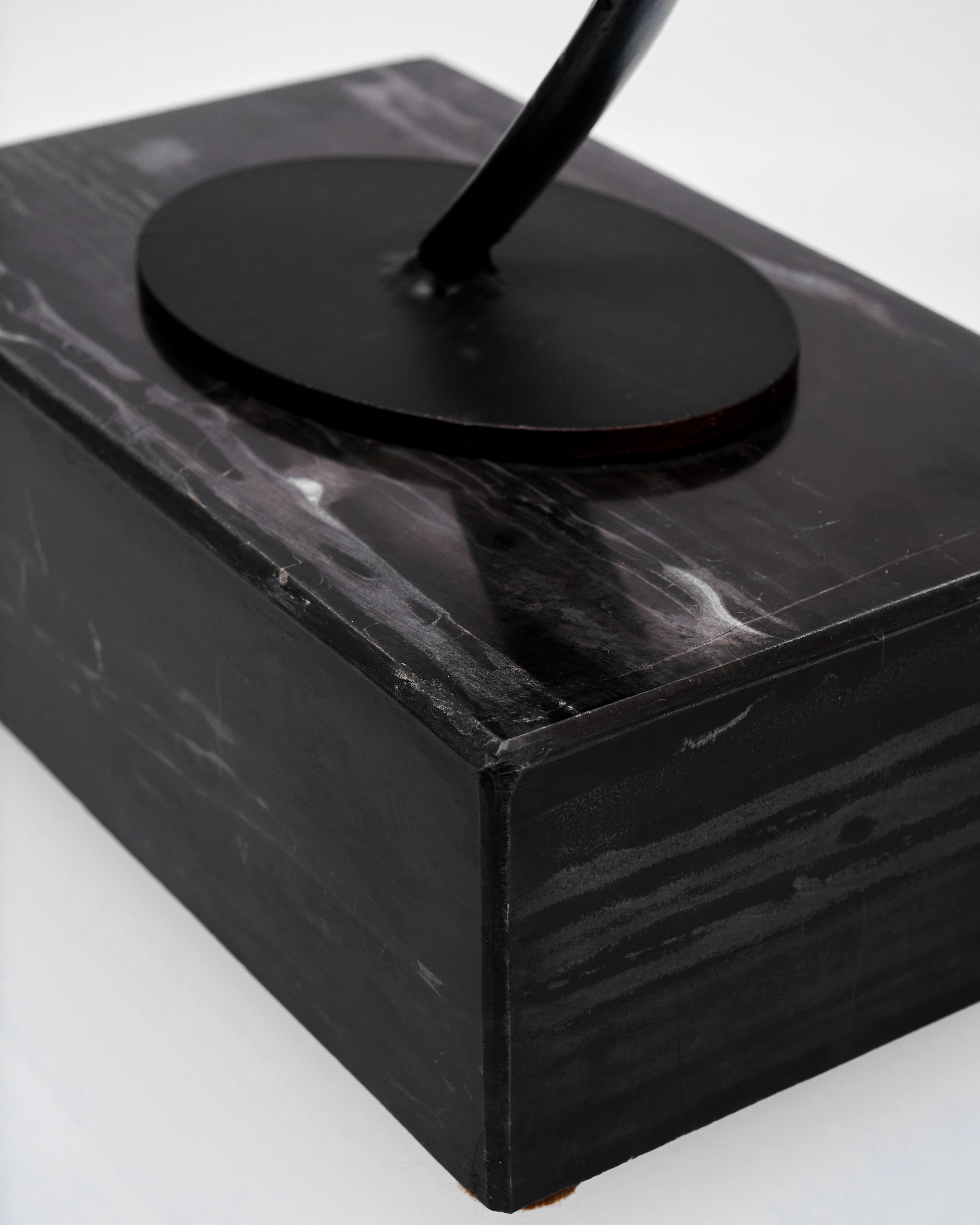 Black marble base with a round black object on top
