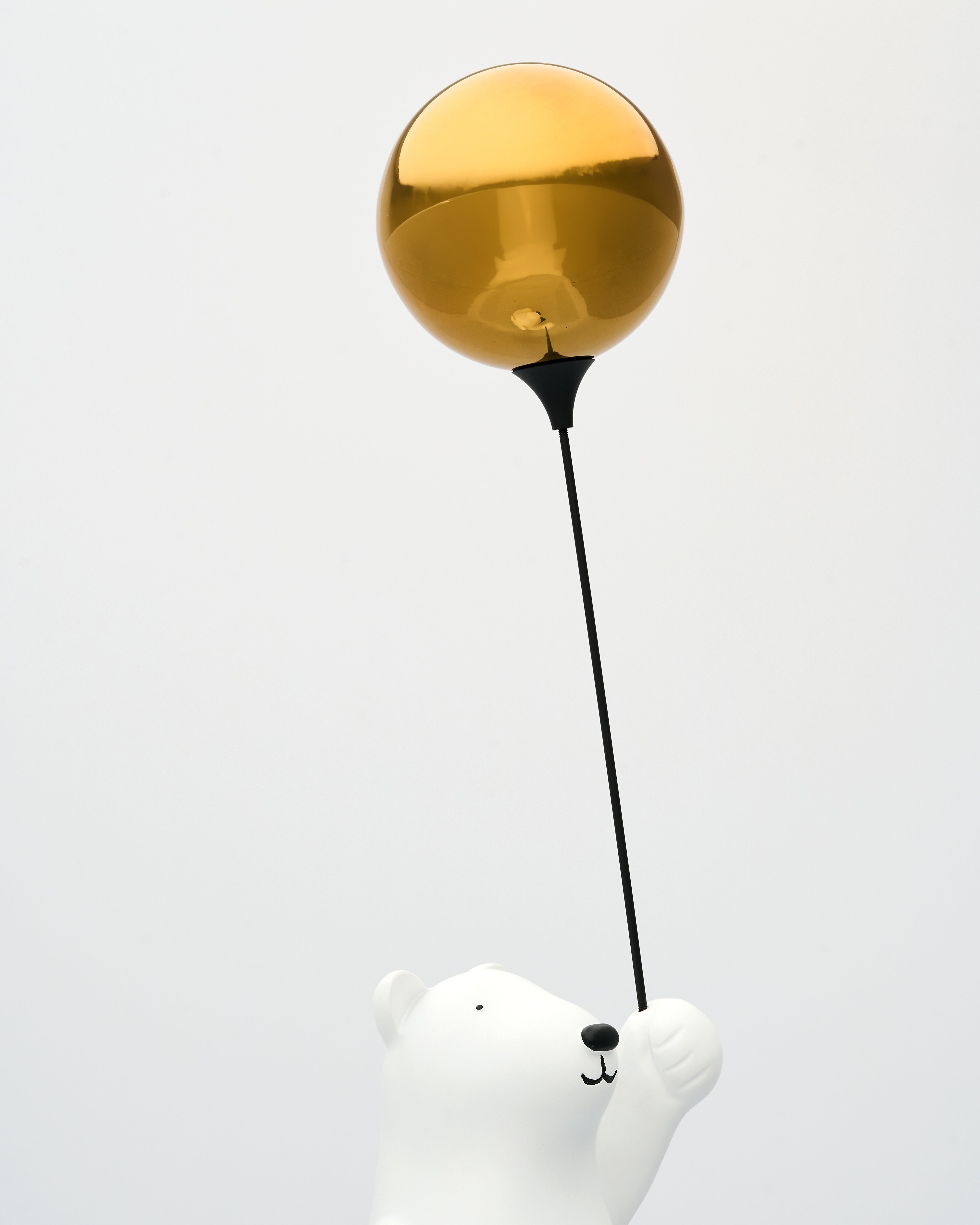 White bear figurine with a gold balloon on a white background