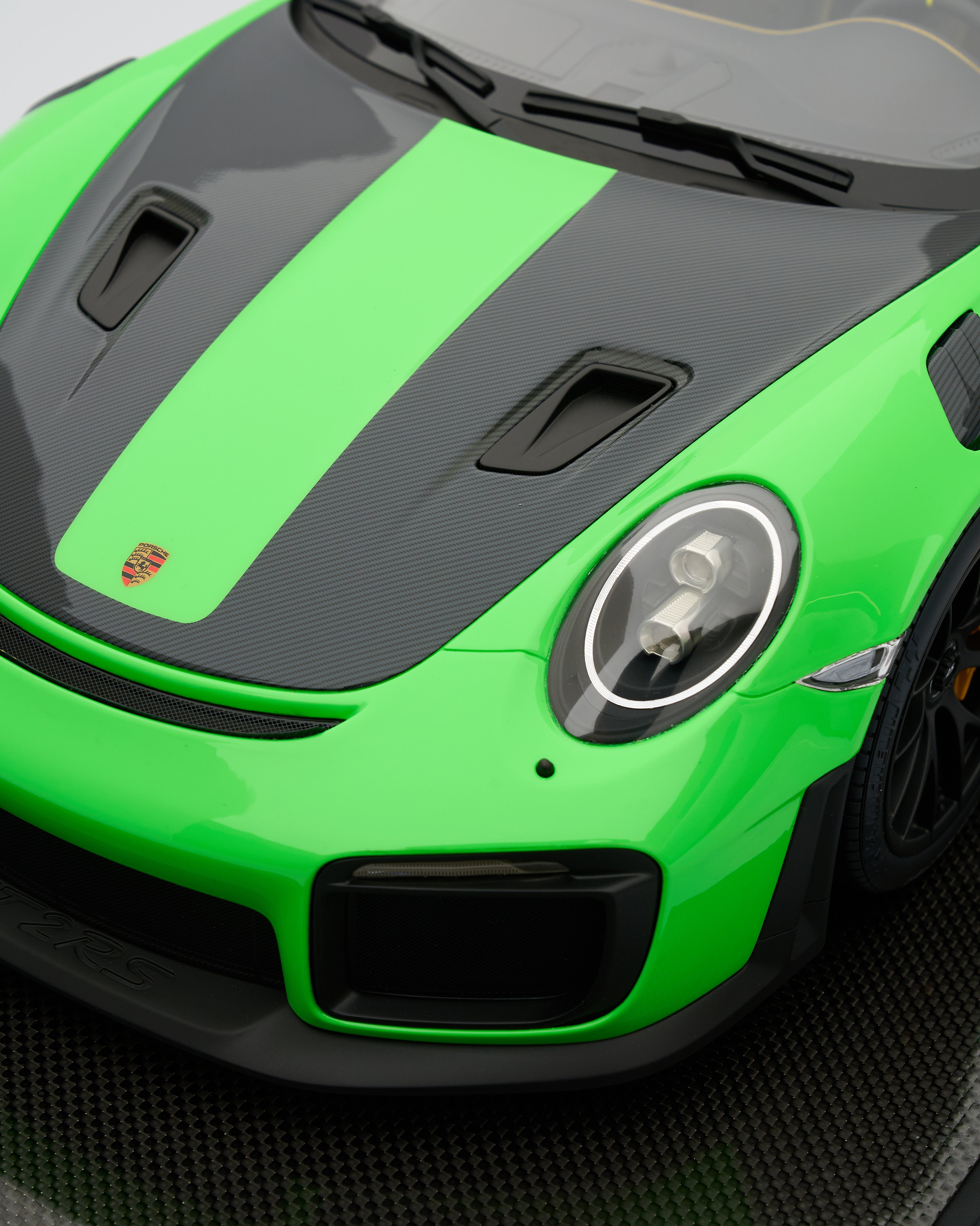 Close-up of a green and black sports car with Porsche logo