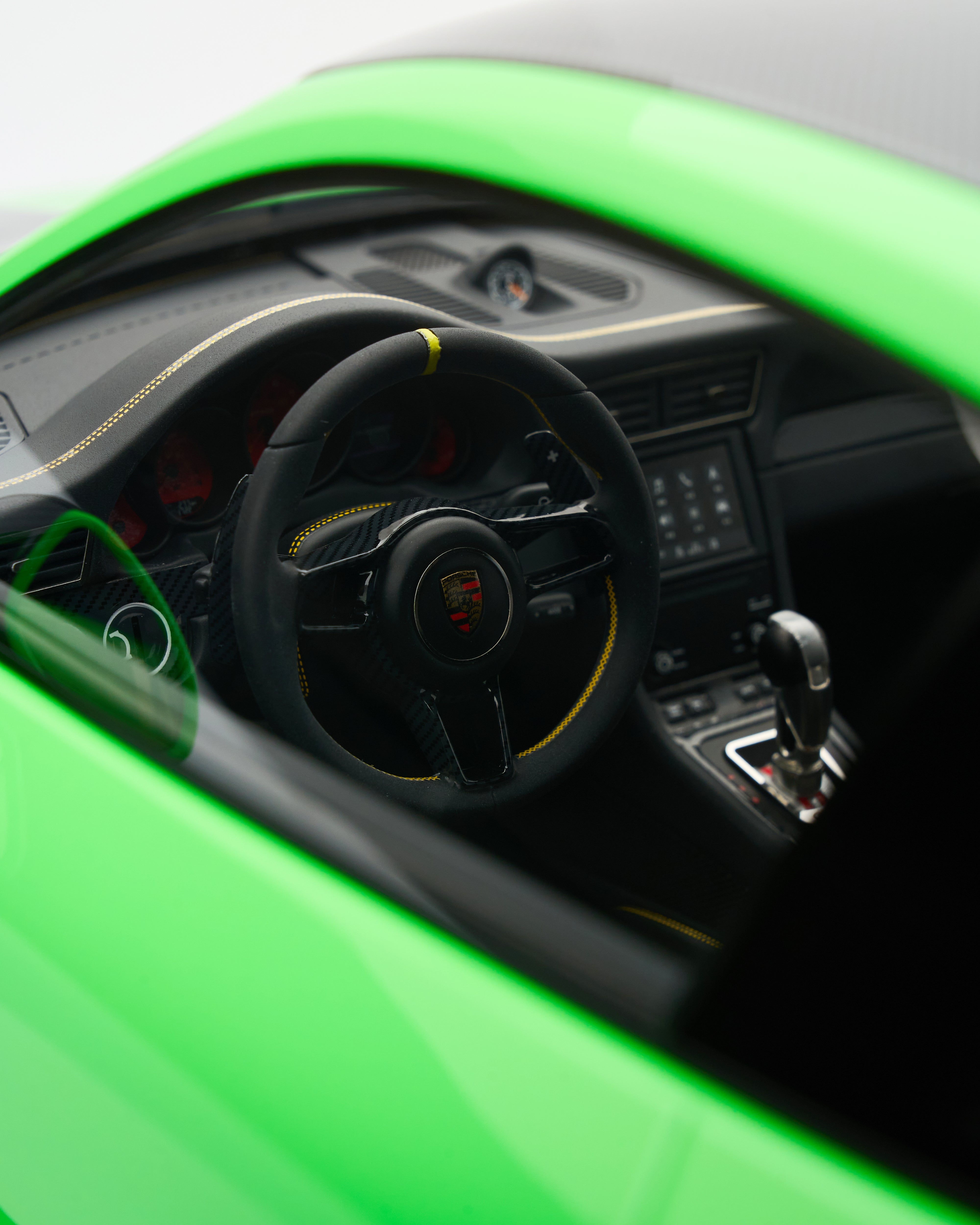 Close-up of a car's steering wheel and dashboard with a green exterior.