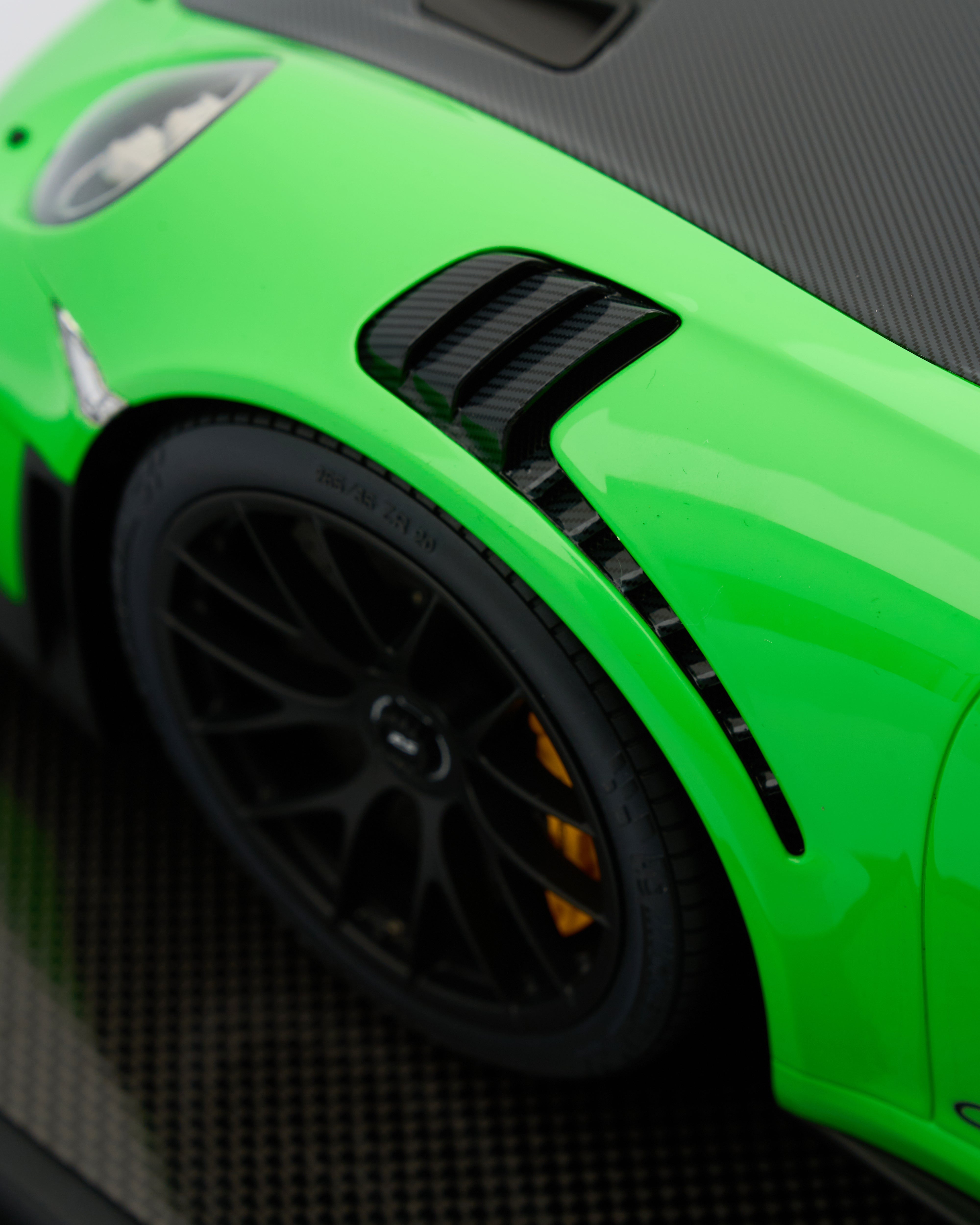 Close-up of a green Porsche 911 GT2RS Viper Green  sports car with black wheel and carbon fiber accents.