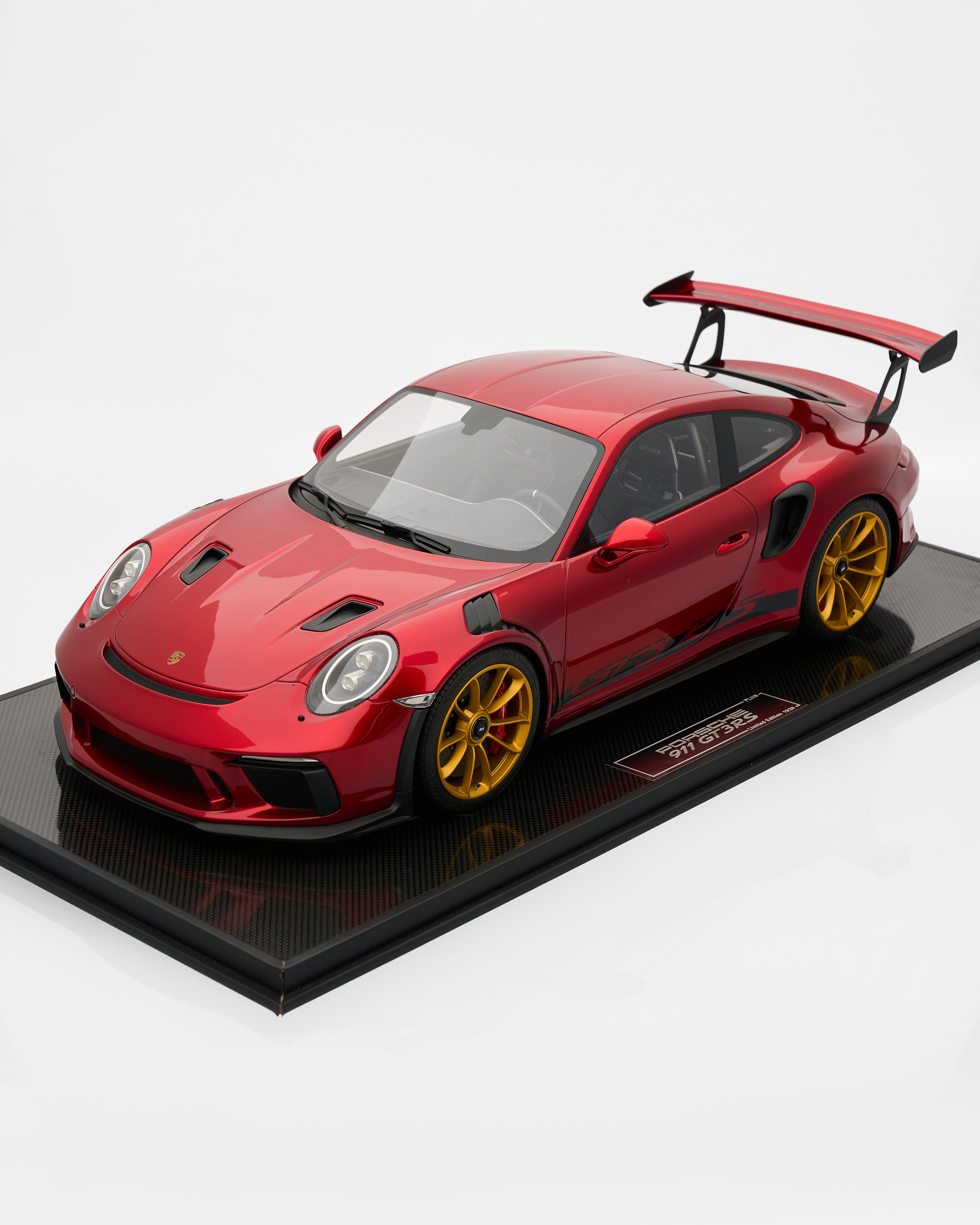 Porsche 911 GT3RS Guards Red sports car model on a black platform with a white background