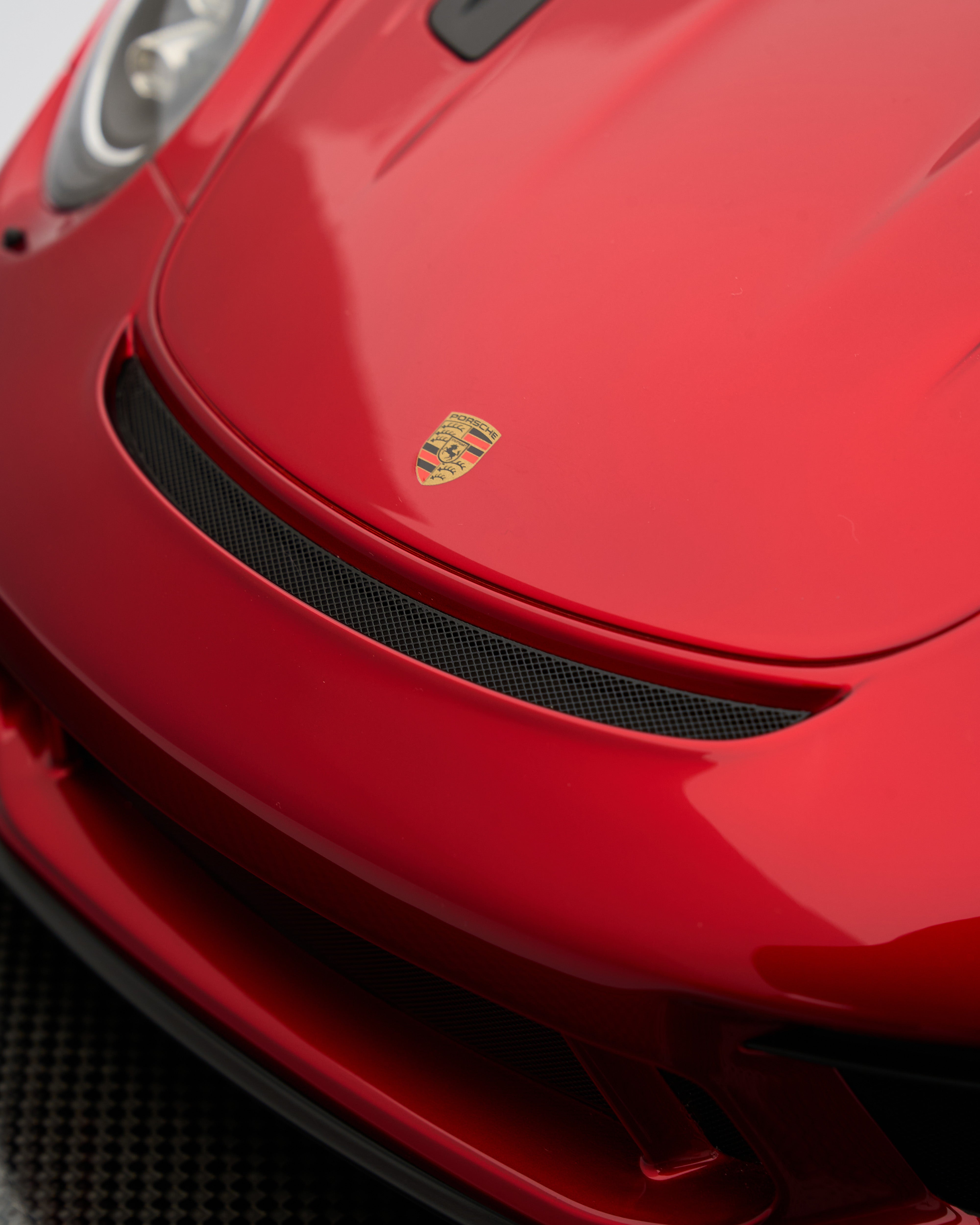 Close-up of a red Porsche car with the brand logo on the hood.