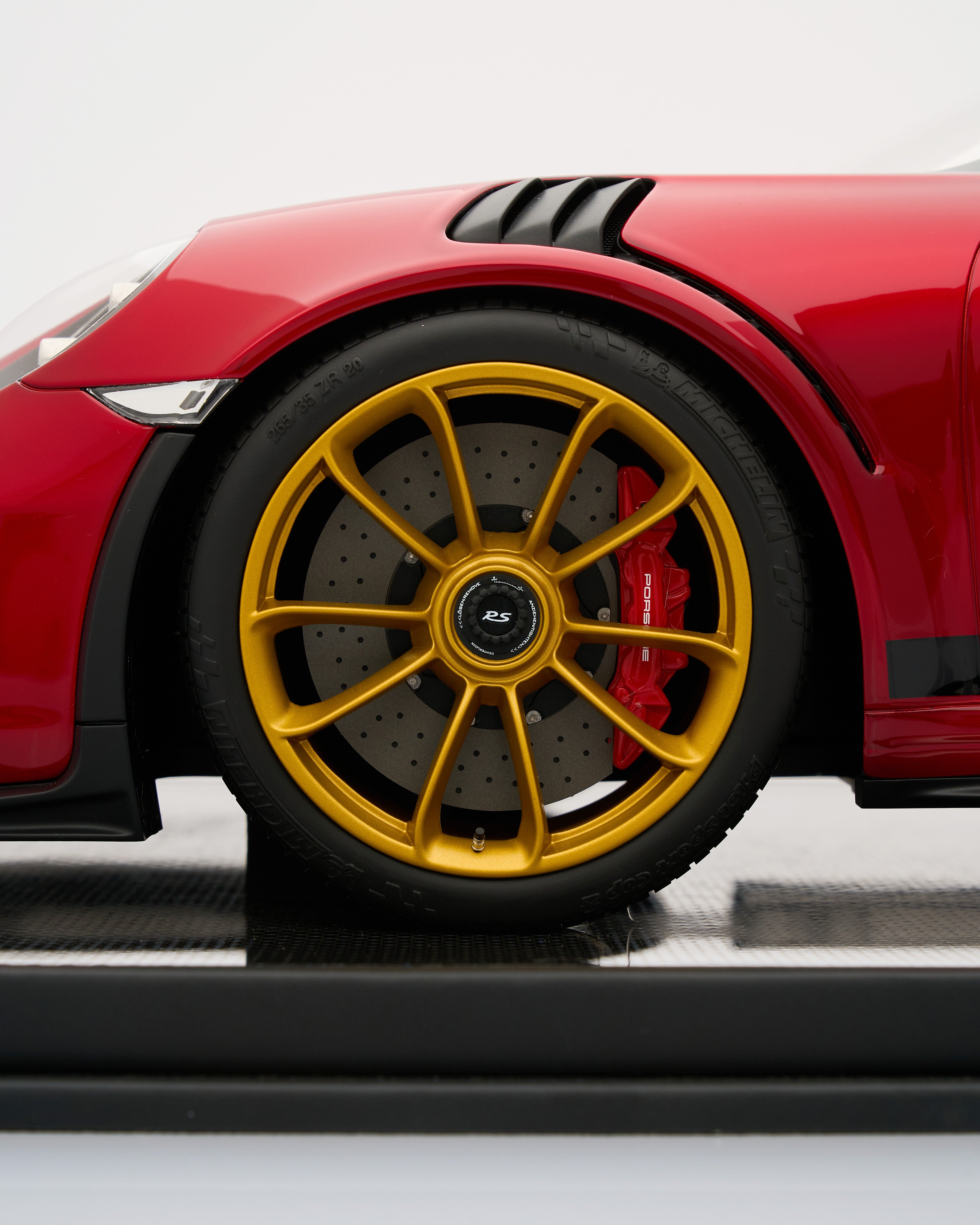 Close-up of a red car with a yellow wheel on a white background