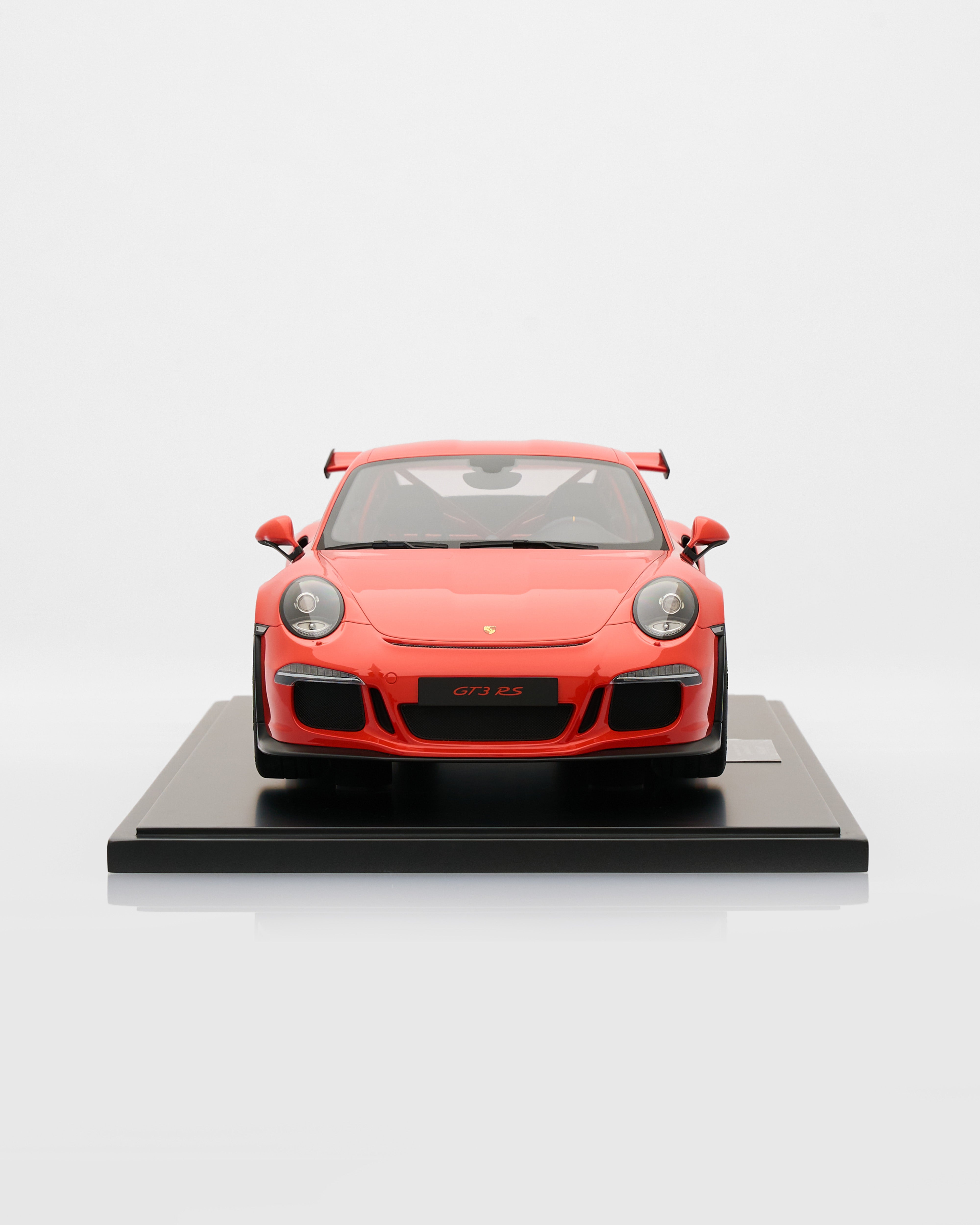 Red Porsche 911 GT3RS Lava Orange model car on a black platform with a white background