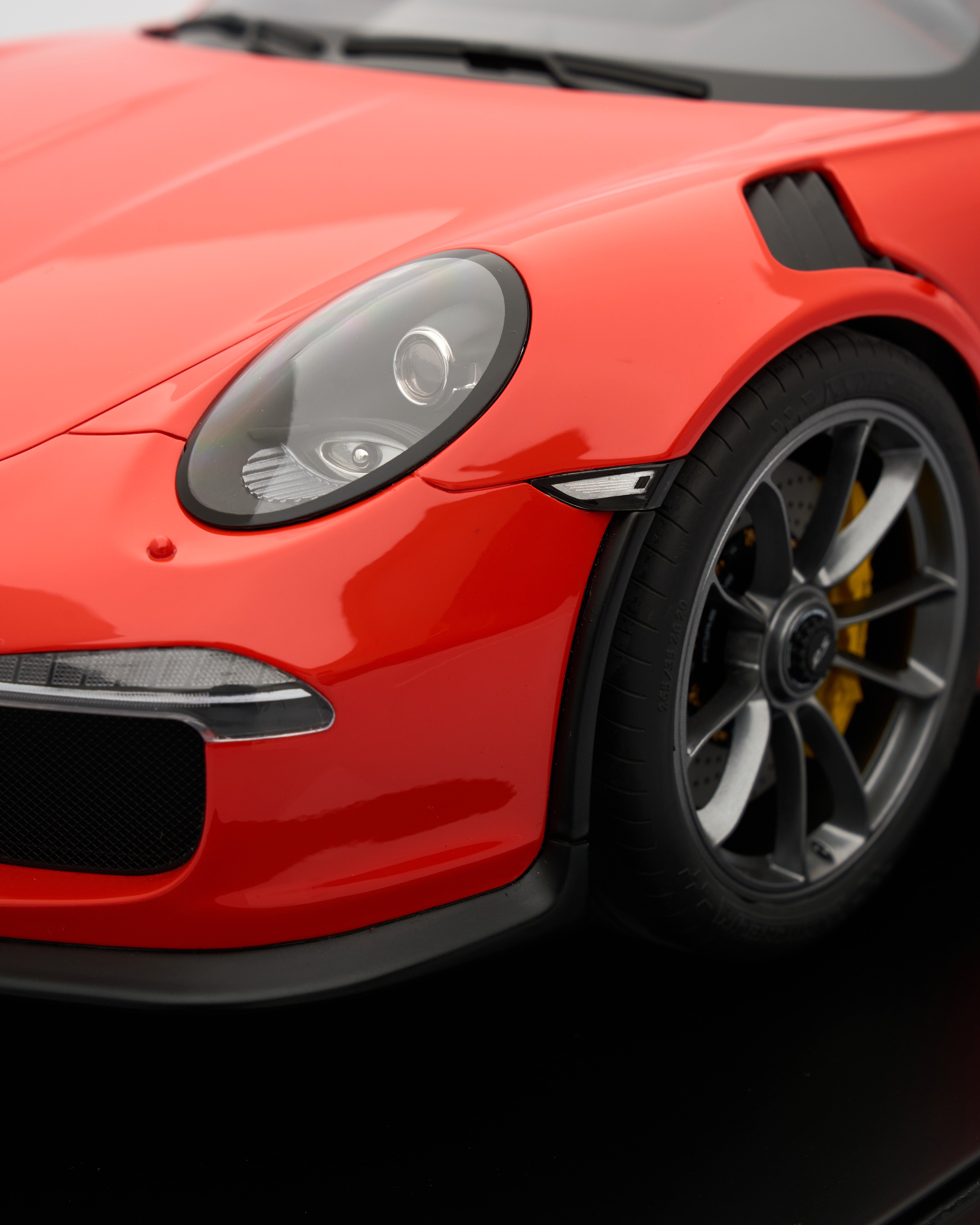 Close-up of a red sports car with black rims on a dark background