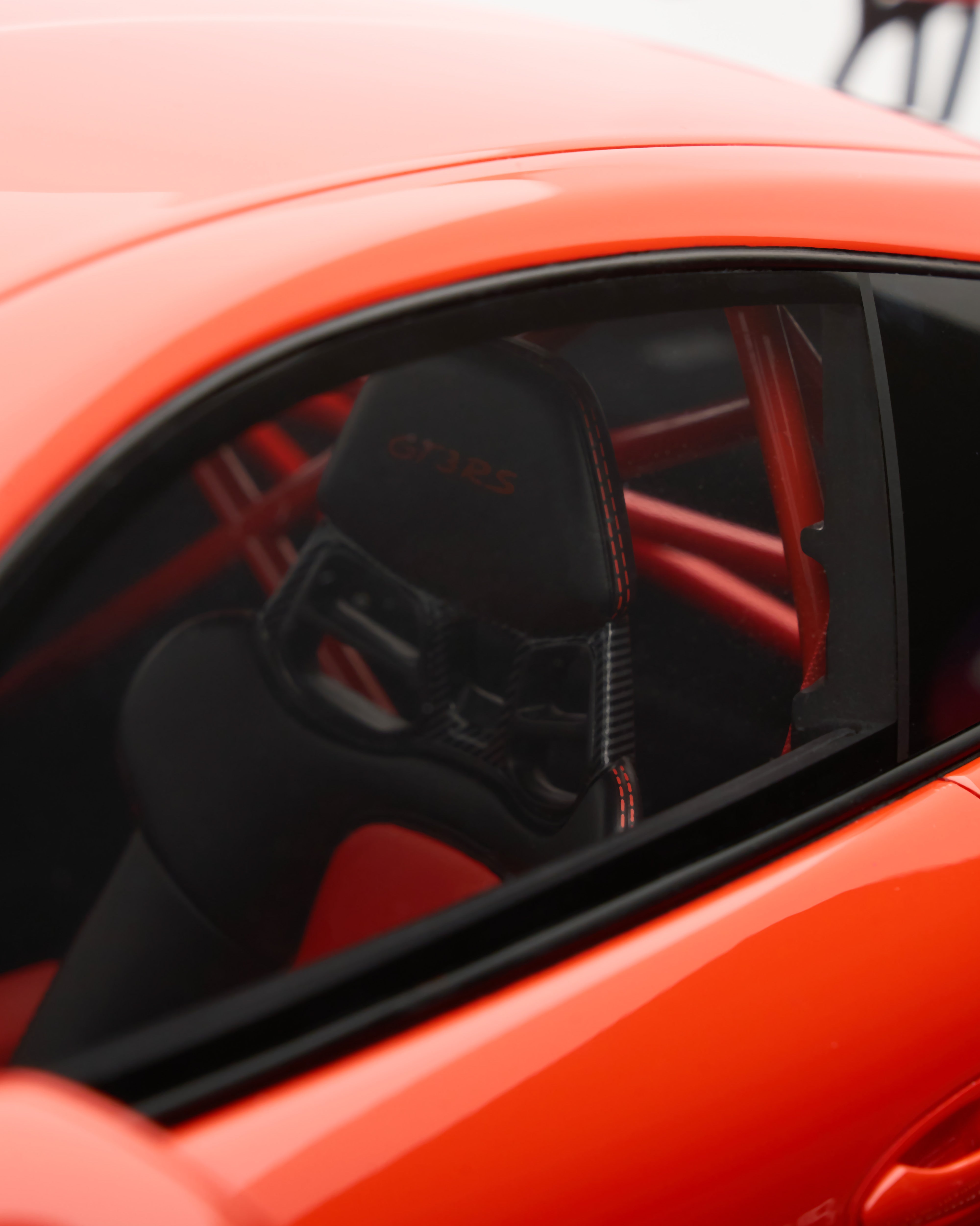 Black racing seat with 'Oreca' branding inside an orange car.