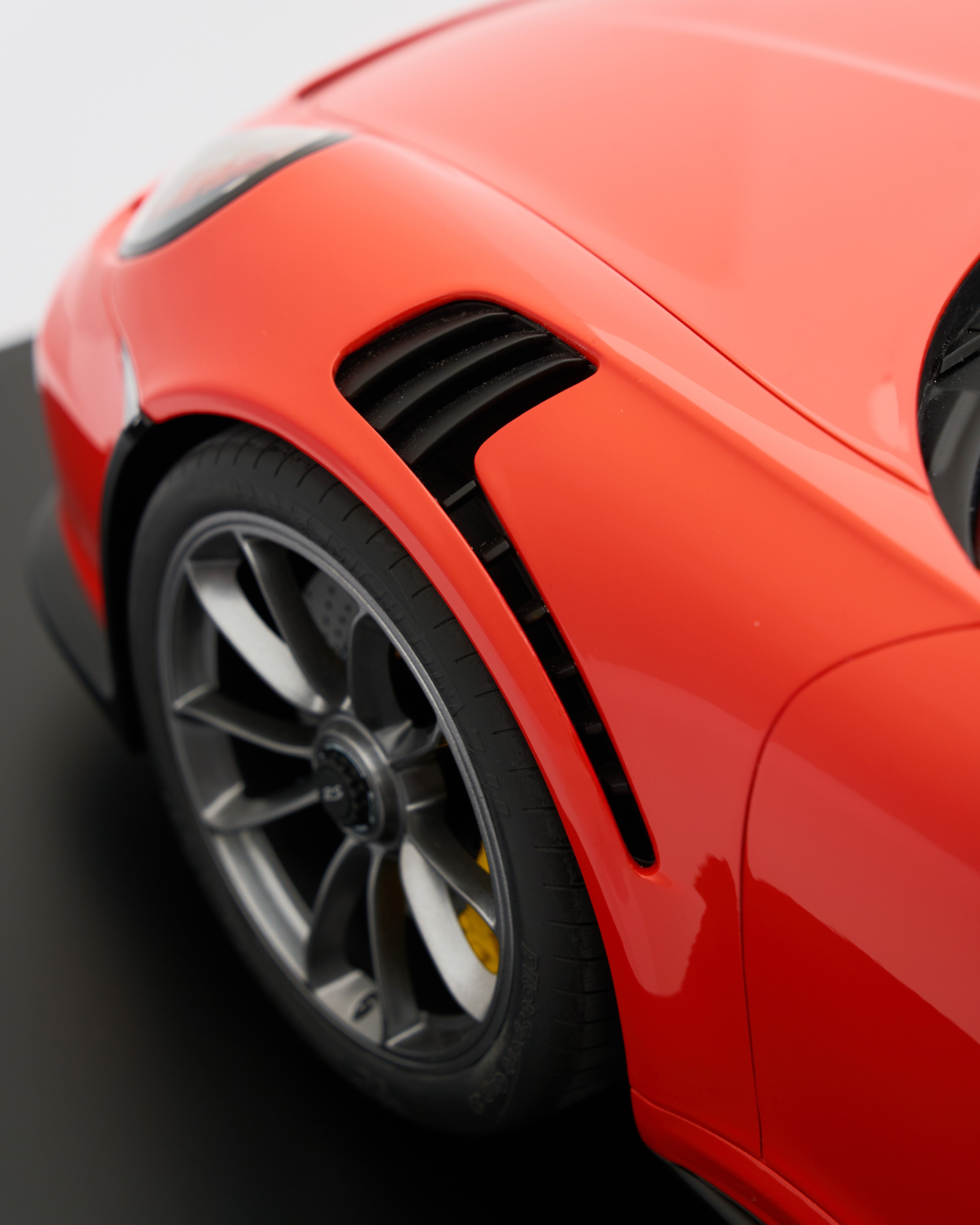 Close-up of a red sports car's wheel and side profile on a blurred background
