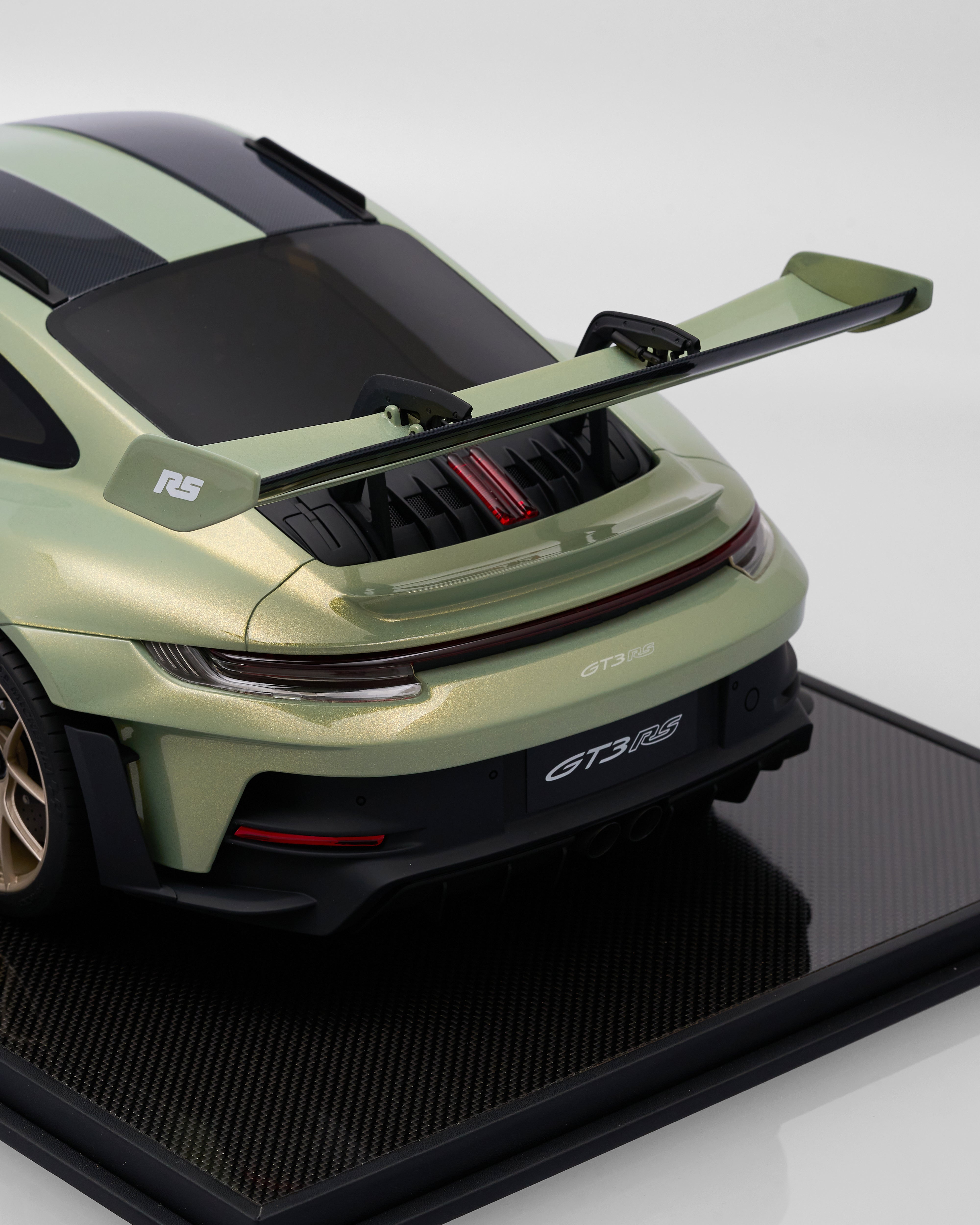 Green sports car model on a black stand with a white background