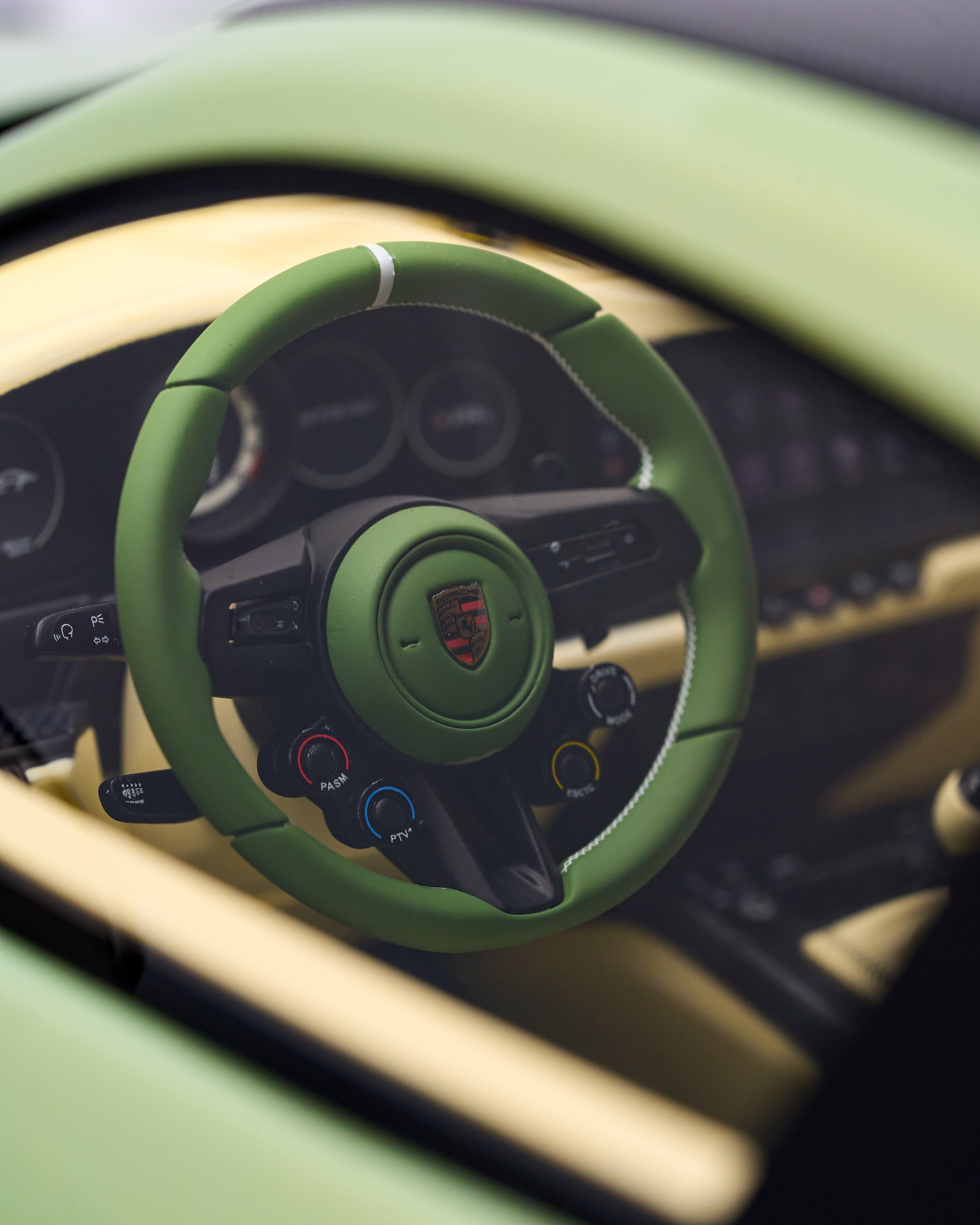 Green steering wheel of Porsche 911 GT3RS Nato Olive Green  with a logo in a car interior