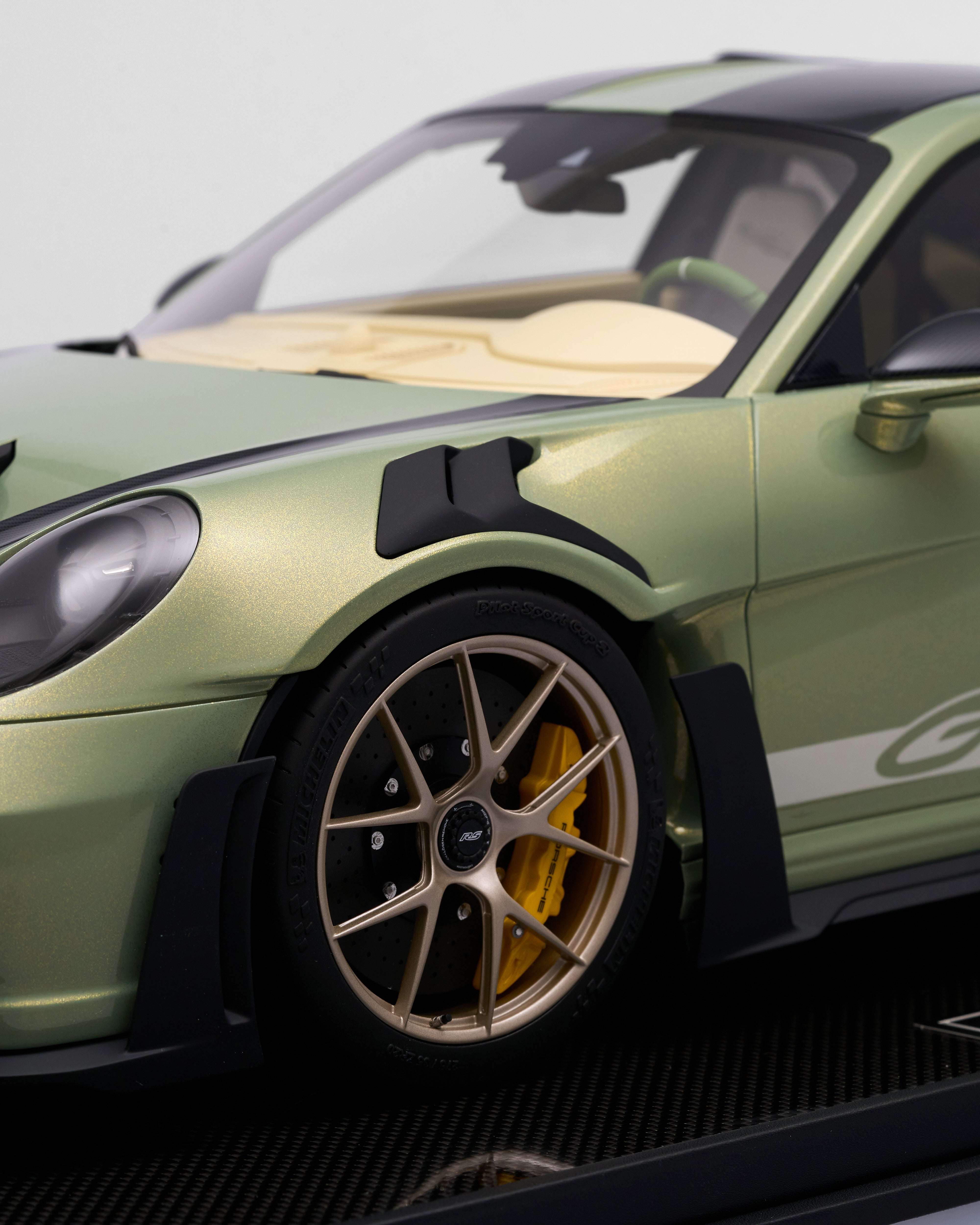 Close-up of a green sports car with a focus on the wheel and front bumper.