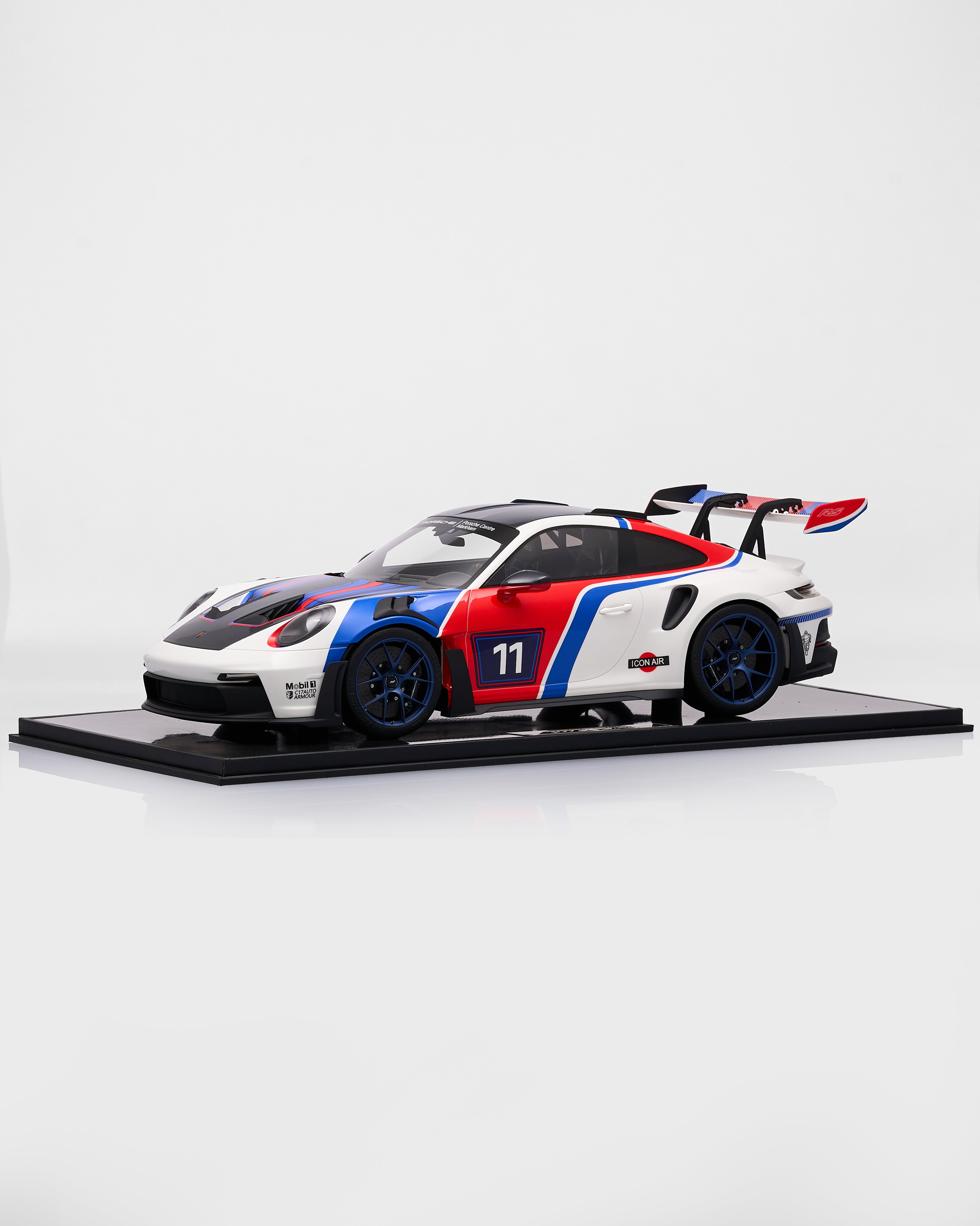 Porsche 911 GT3RS R Rennsport  with a white, red, and blue design on a black platform against a white background