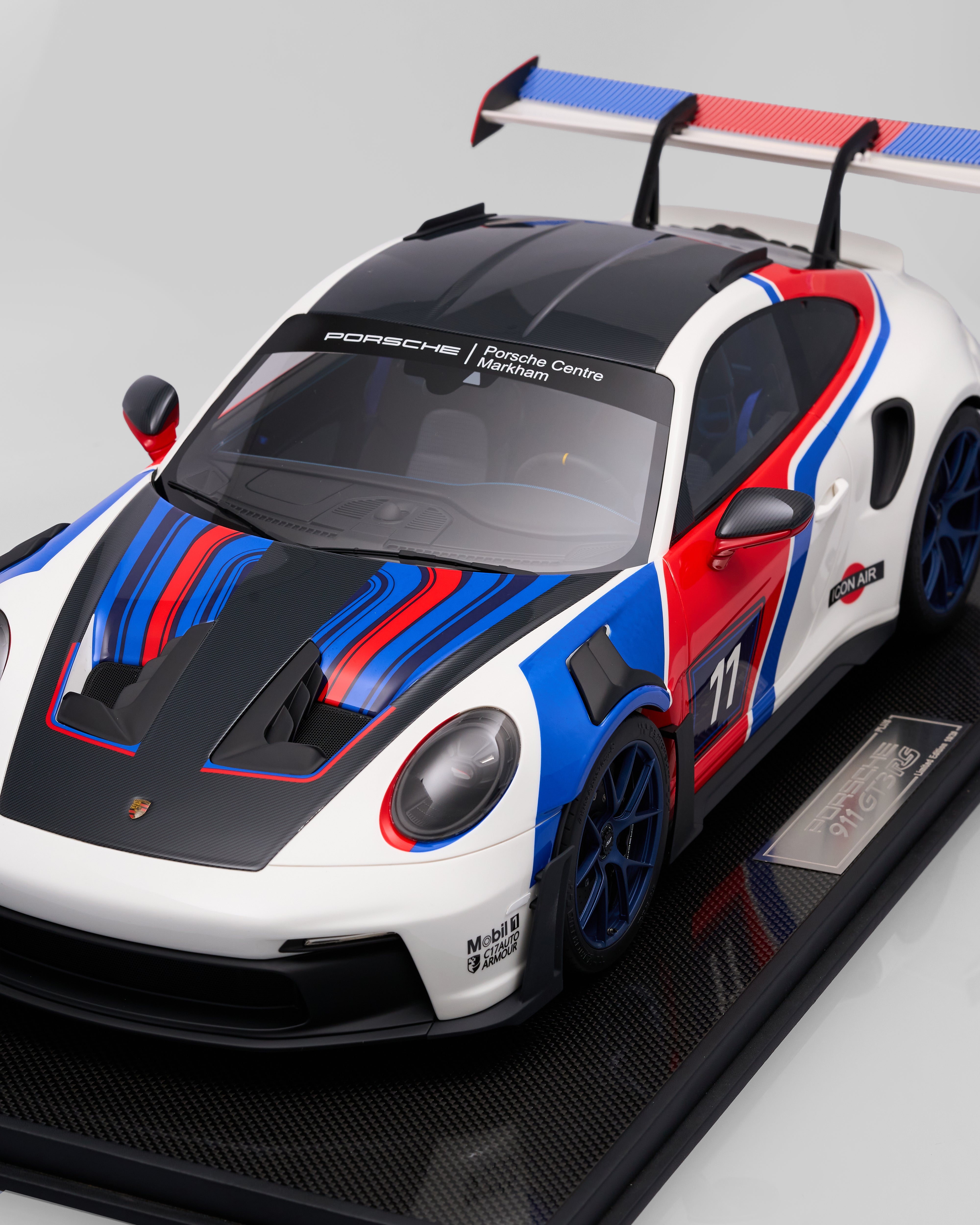 Model of a Porsche race car with red, white, and blue design on a gray background