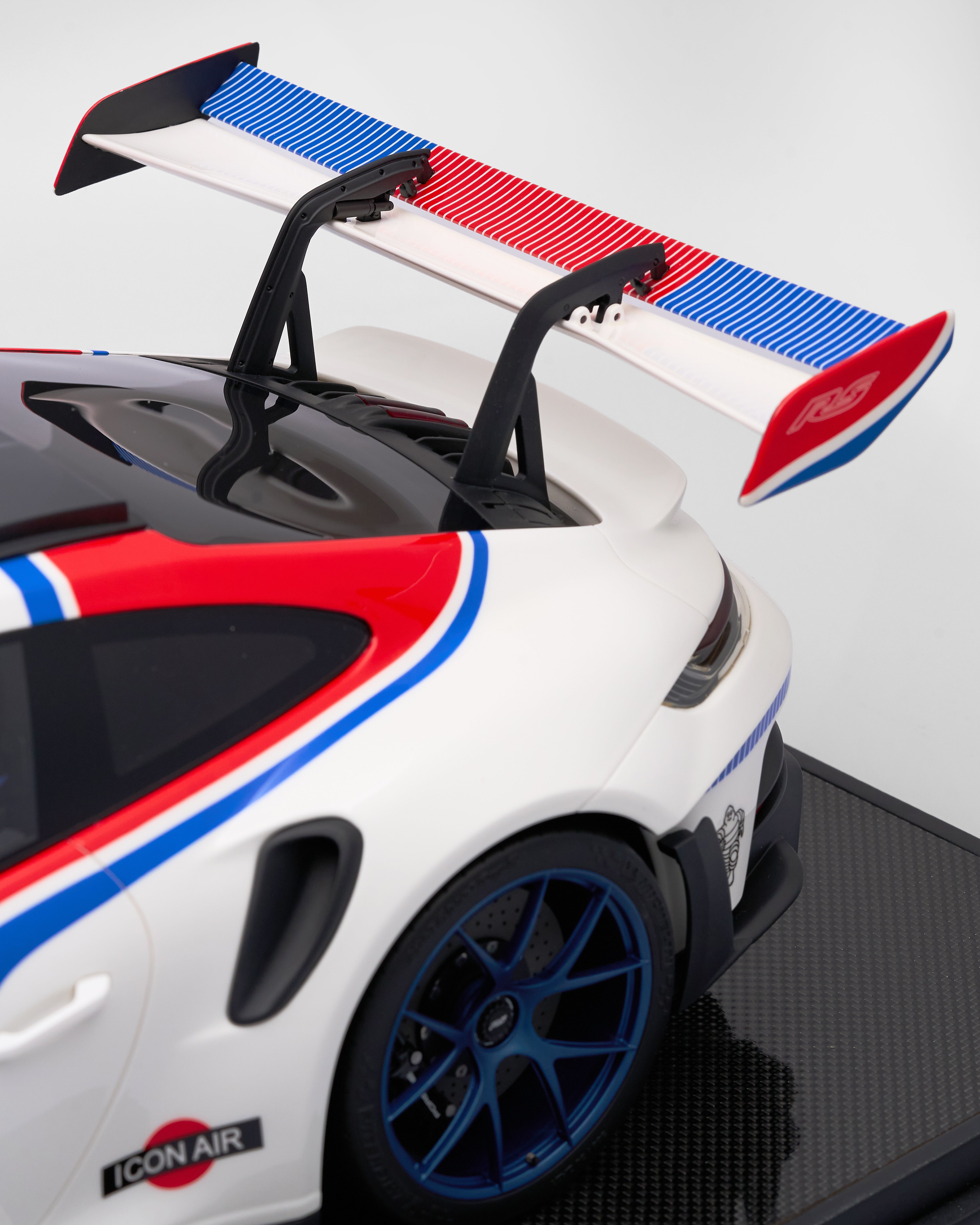 Close-up of a Porsche 911 GT3RS R Rennsport with red and blue accents on a white background