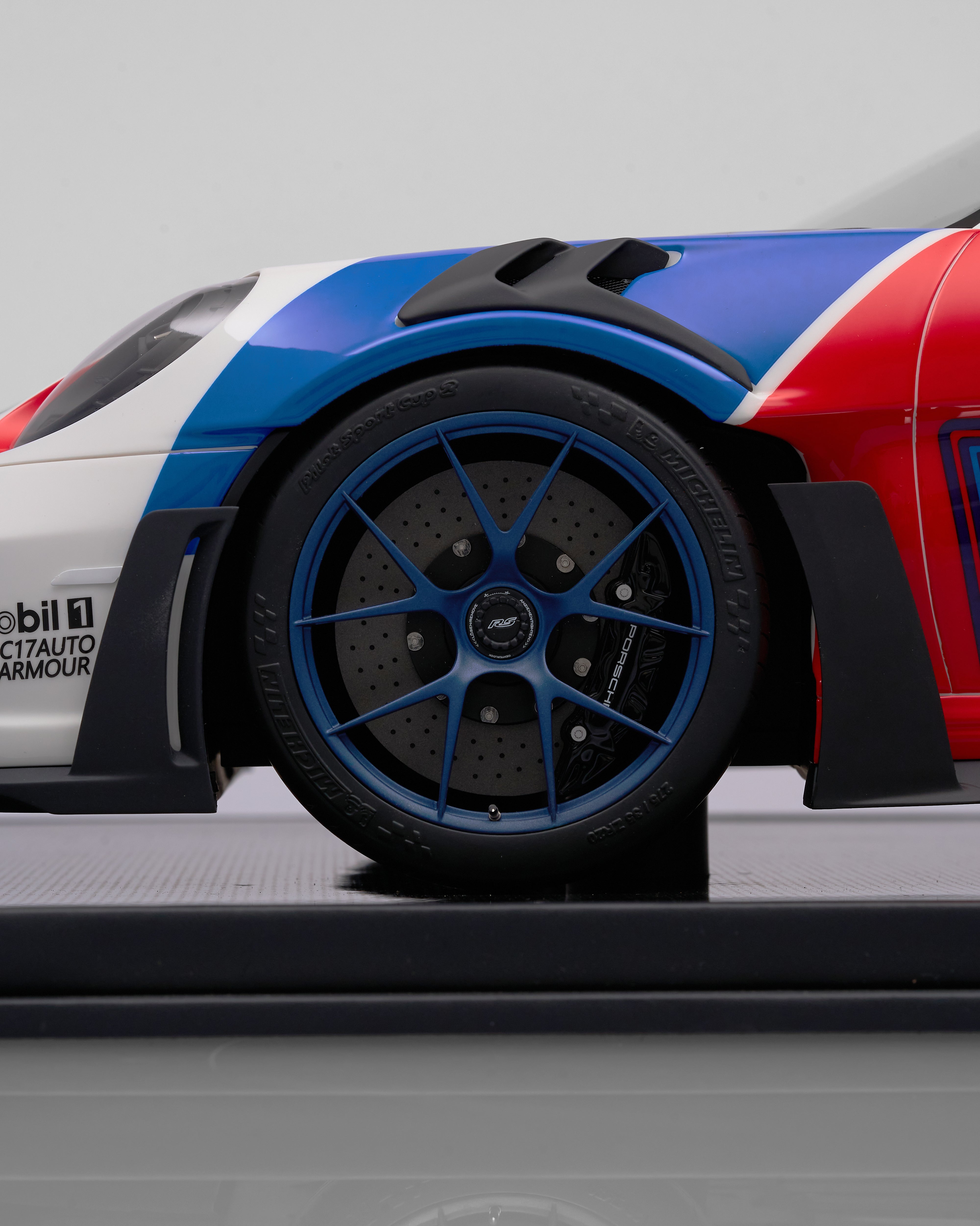Close-up of a race car wheel with a red, white, and blue design on a gray background