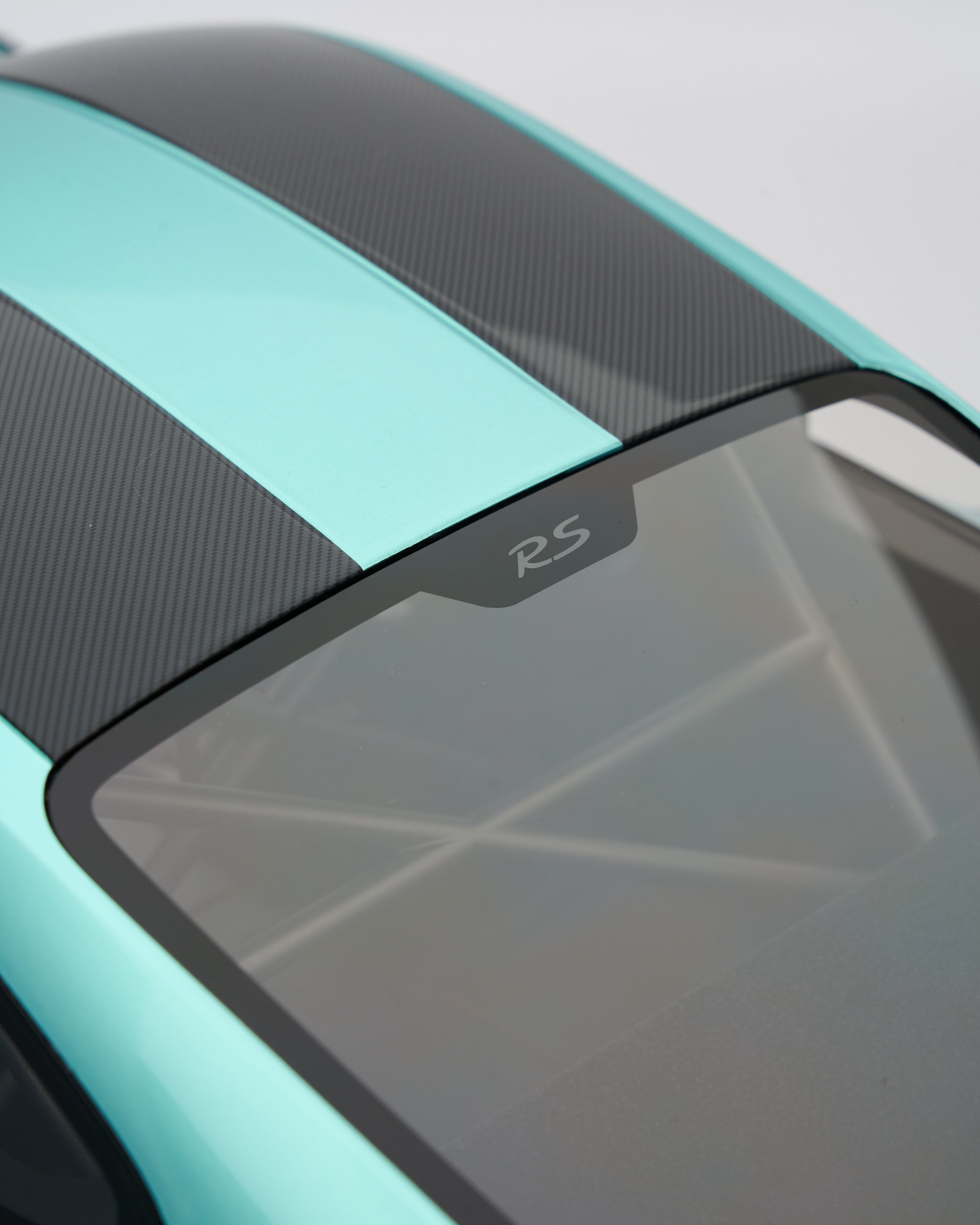 Close-up of a Porsche_GT2RS_Mint_Green_steering roof with 'RS' badge on a teal and black vehicle.