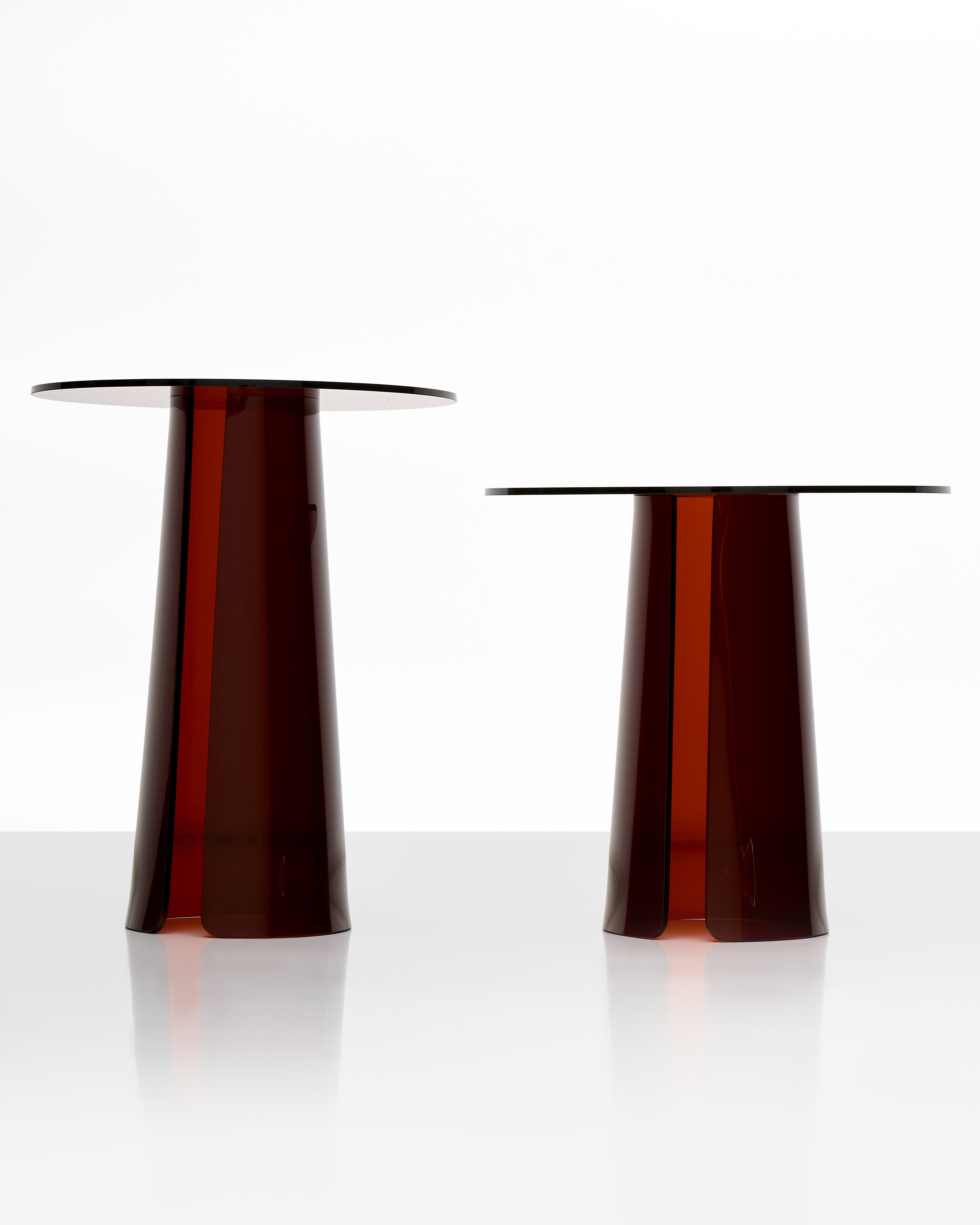 Two dark brown acrylic side table objects on a white background
