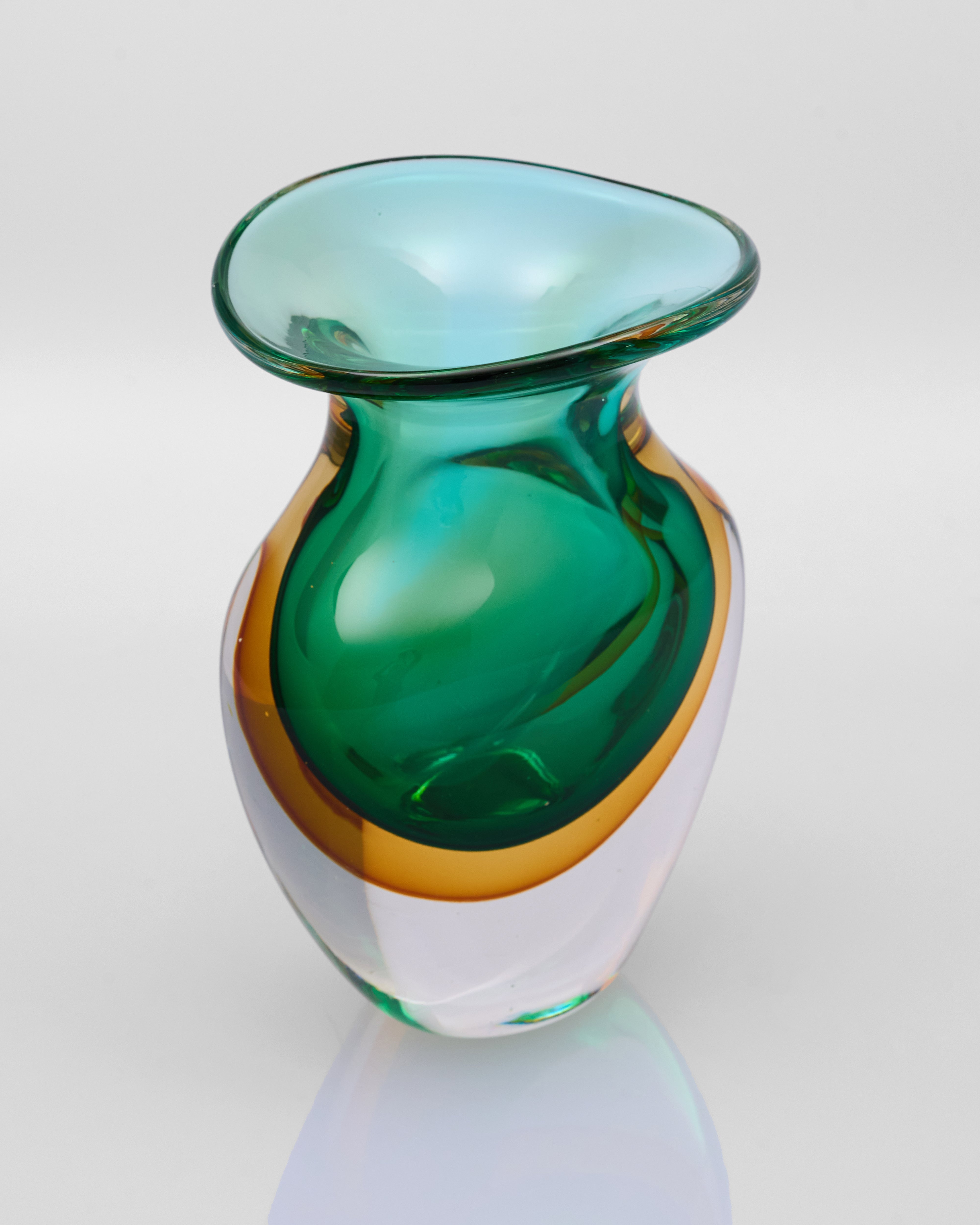 Green glass vase with a white base on a light gray background