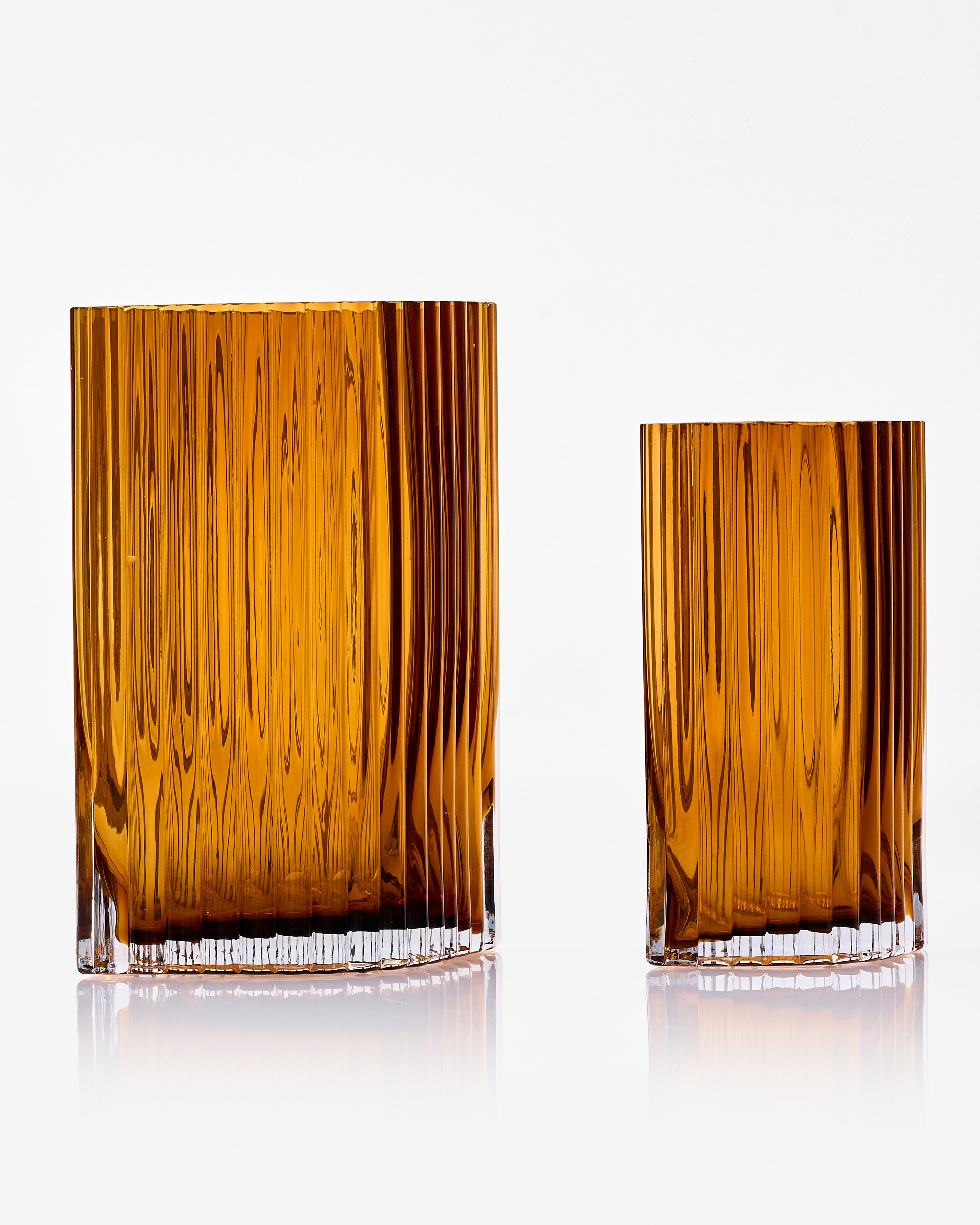 Two amber-colored glass tumblers on a white background