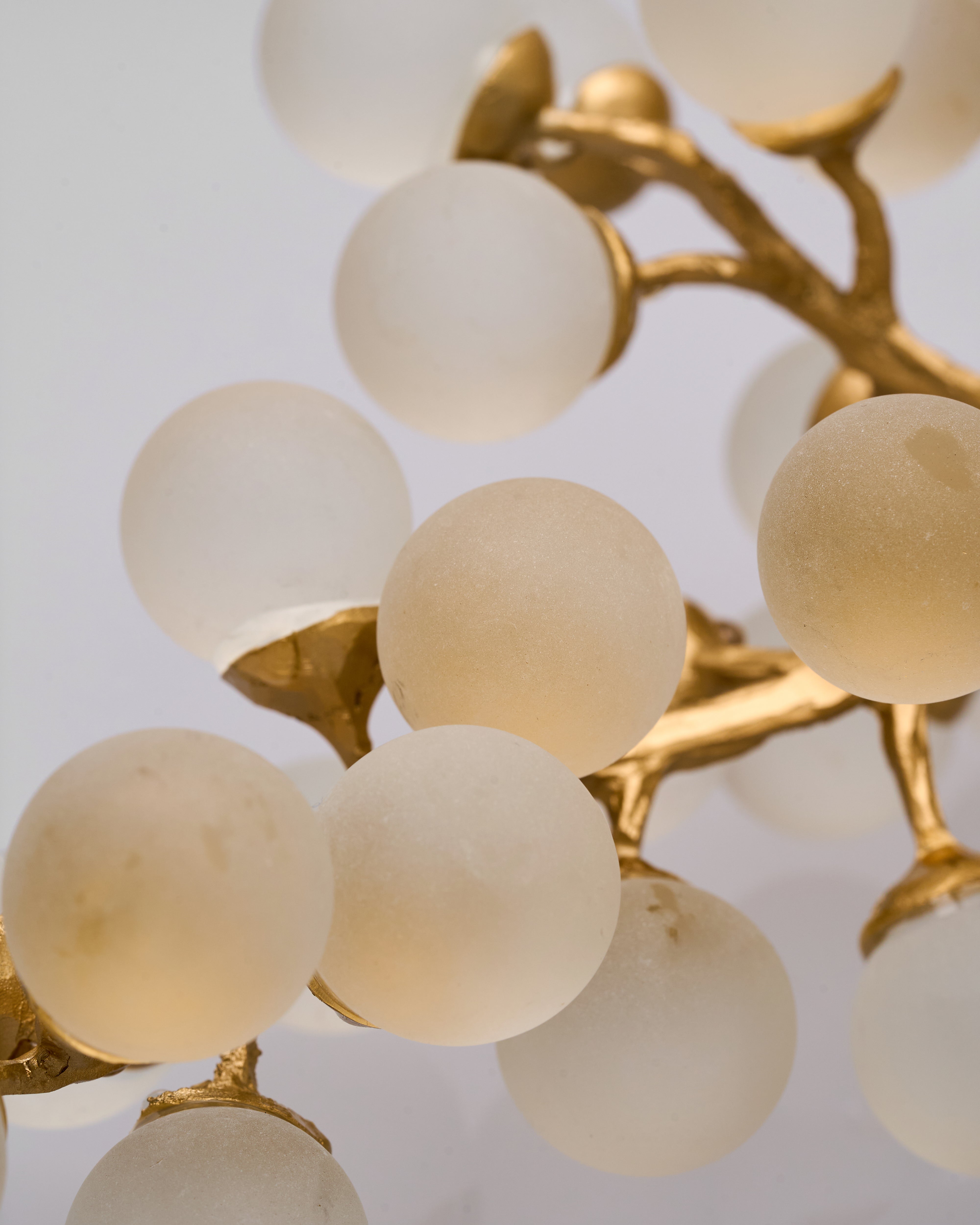 Chandelier with gold frame and white glass spheres on a light gray background