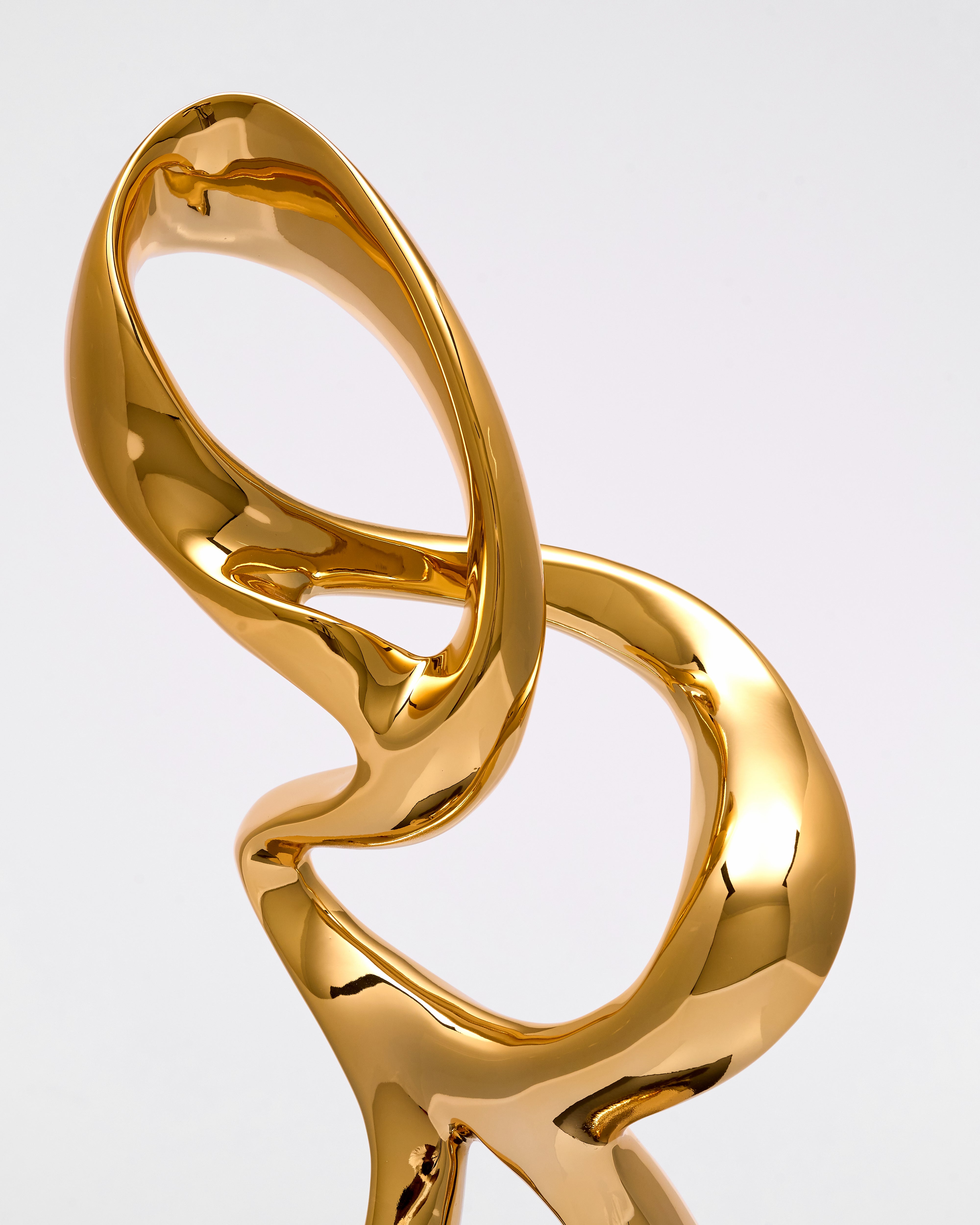 Gold infinity symbol resin sculpture on a light gray background