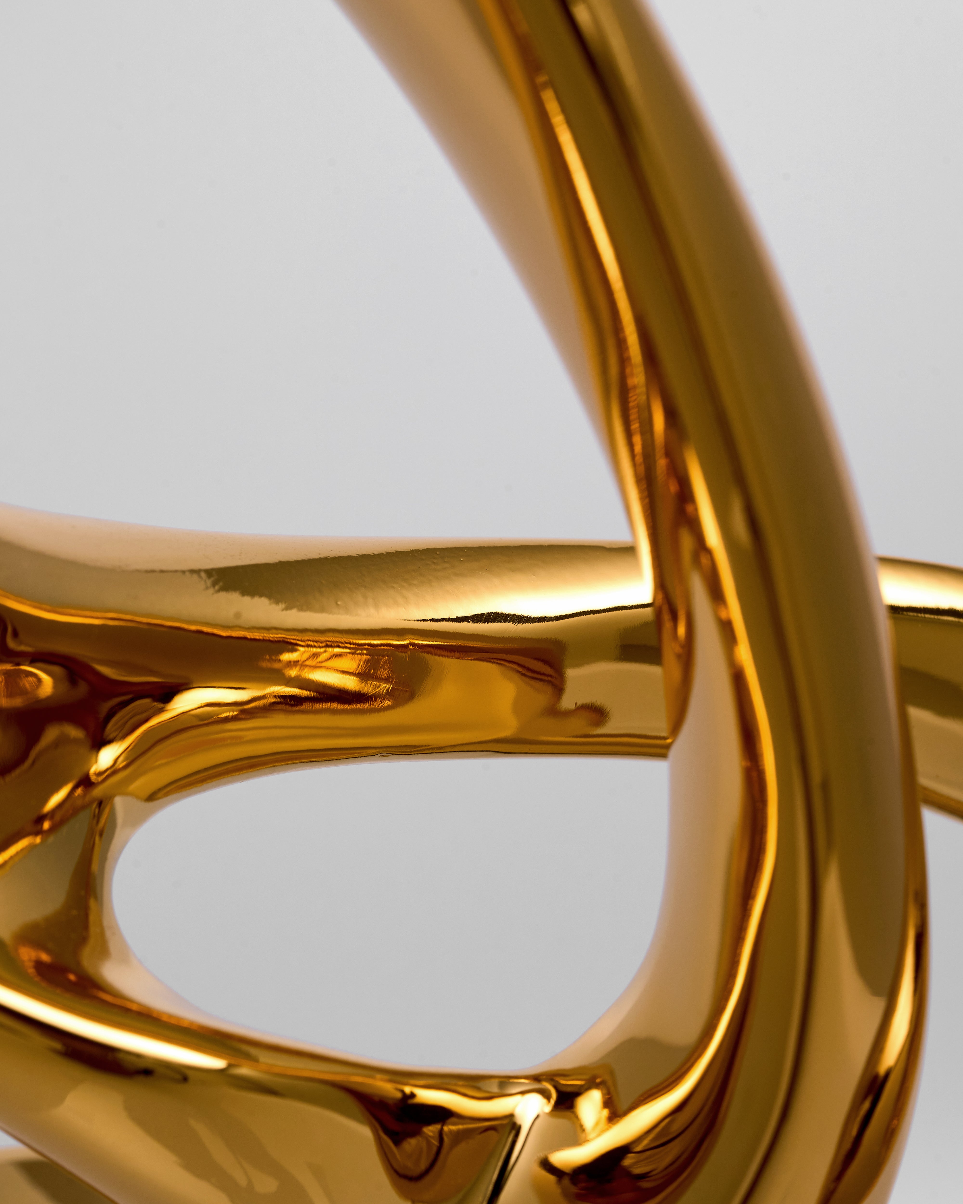 Close-up of a gold resin sculpture with a reflective surface on a light gray background