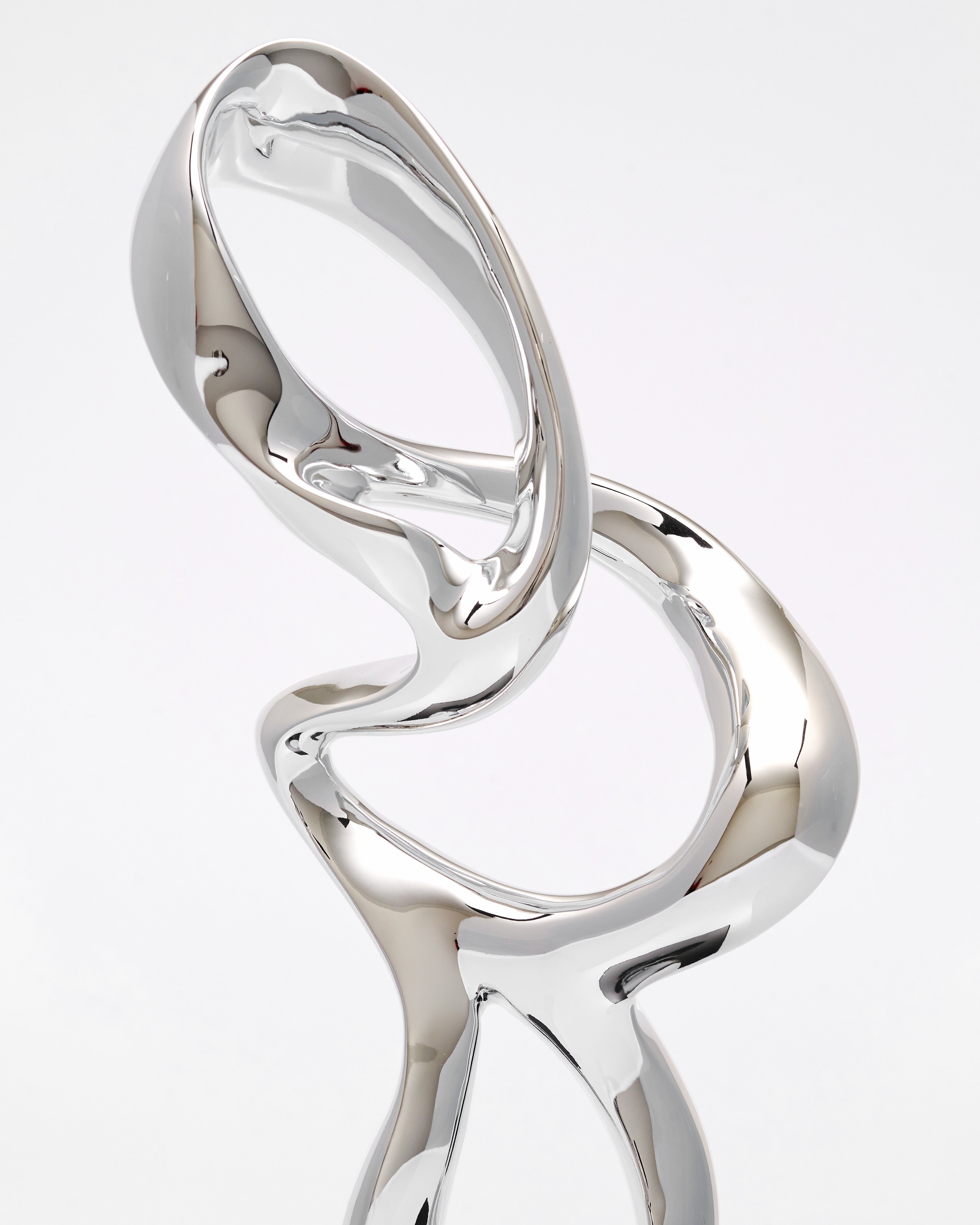 Silver ring with a unique, twisted design on a light gray background