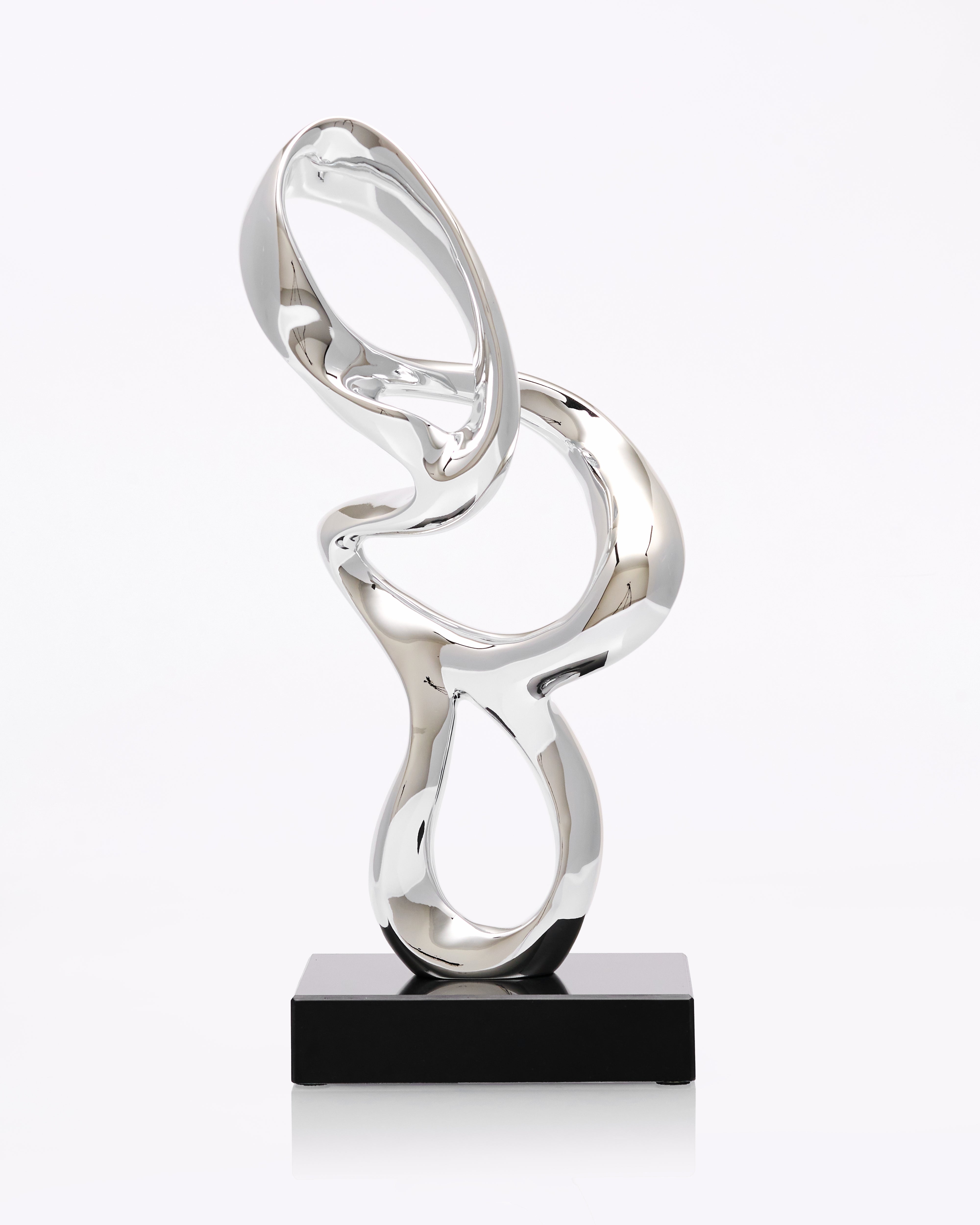 Silver abstract sculpture on a black base against a white background