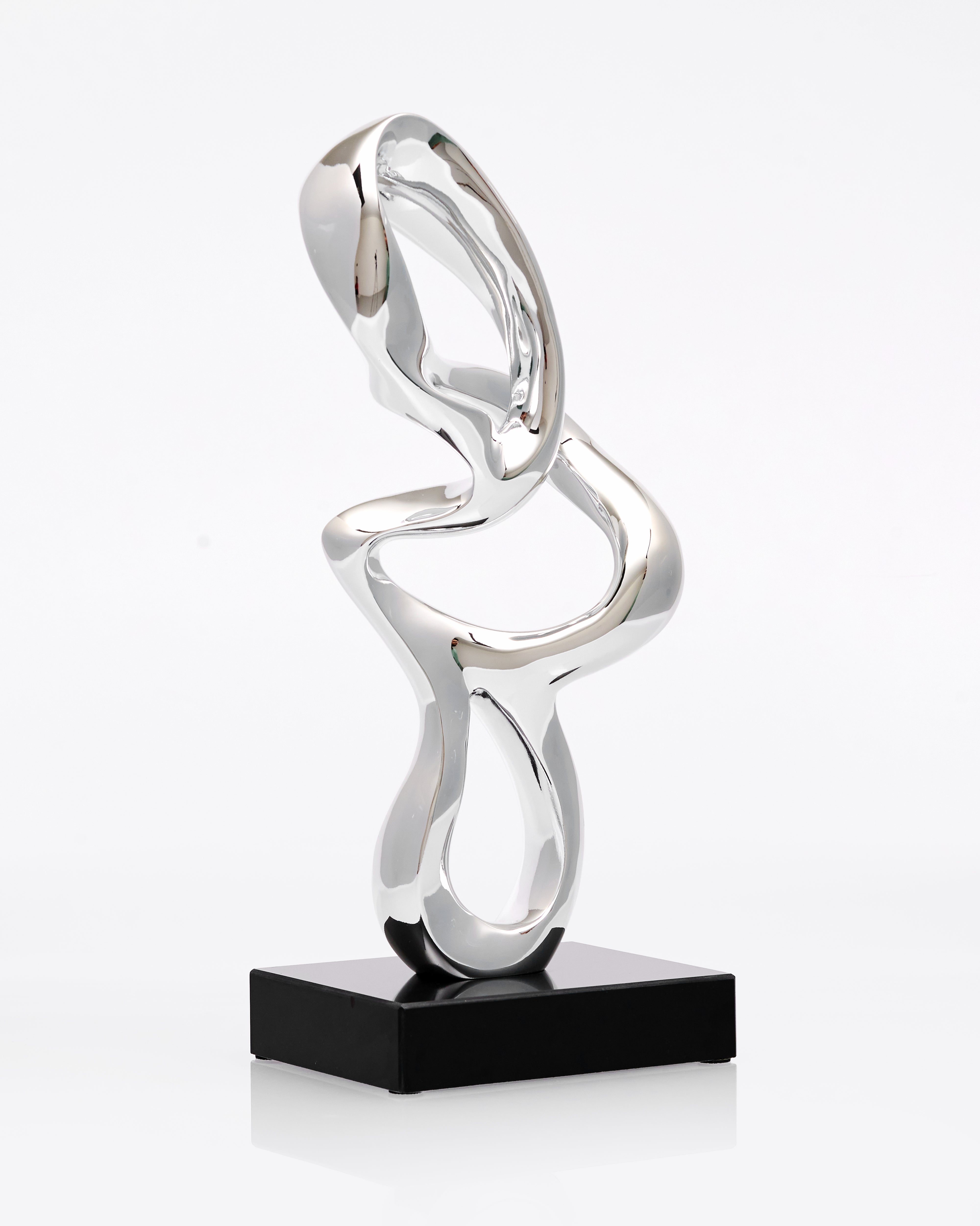 Silver abstract sculpture on a black base against a white background