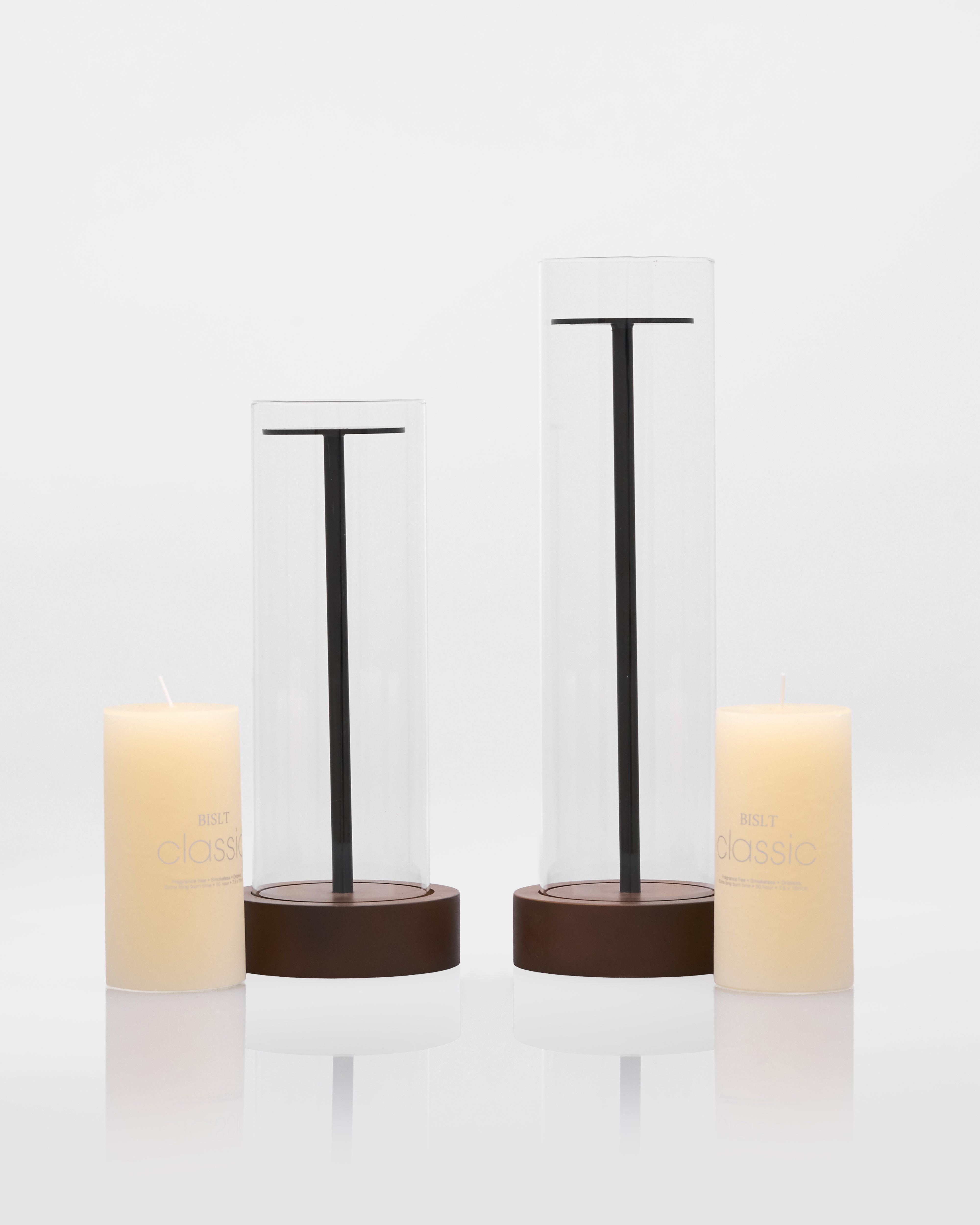 Two candle holders with candles inside on a white background