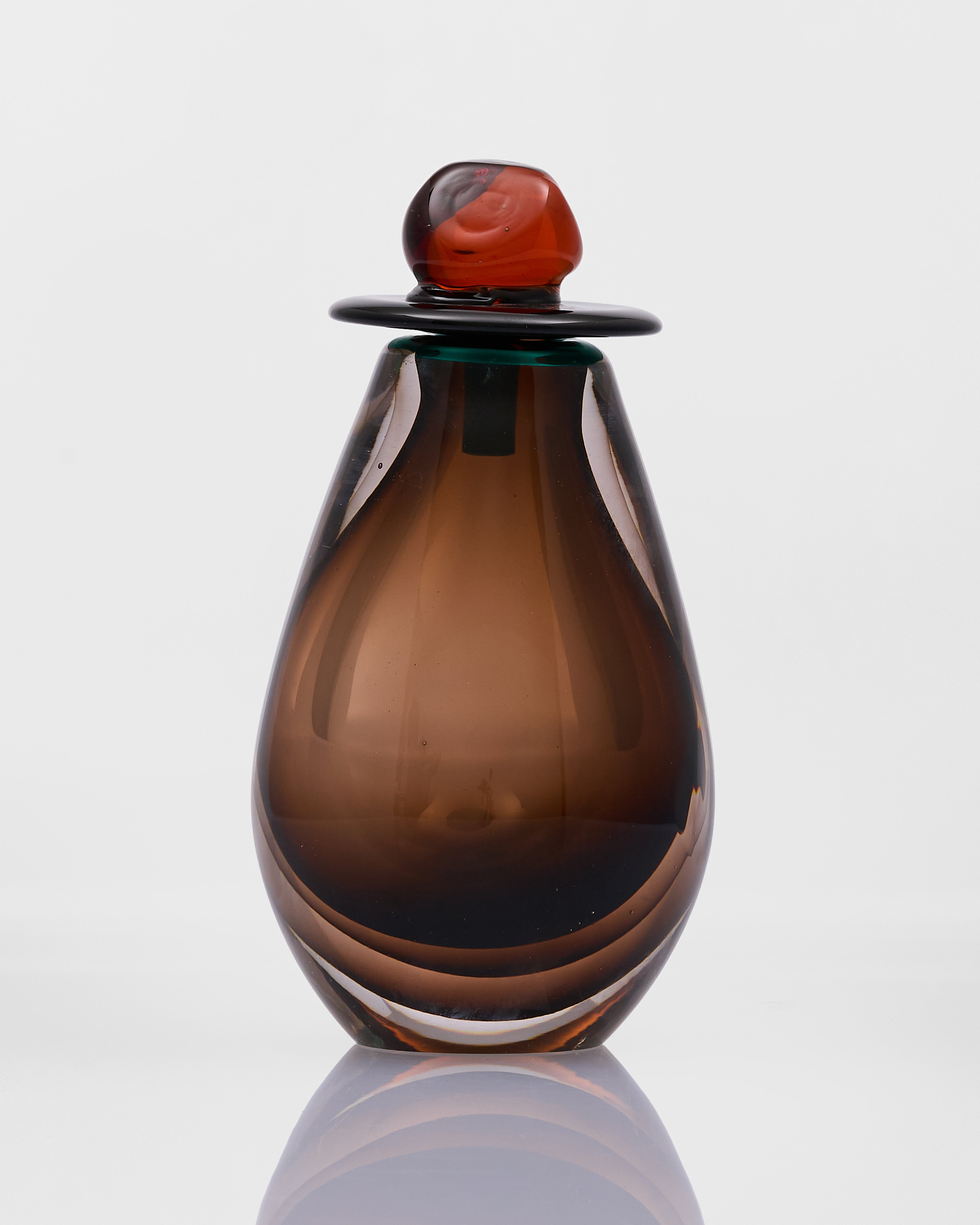 Brown glass bottle with a decorative cap on a white background