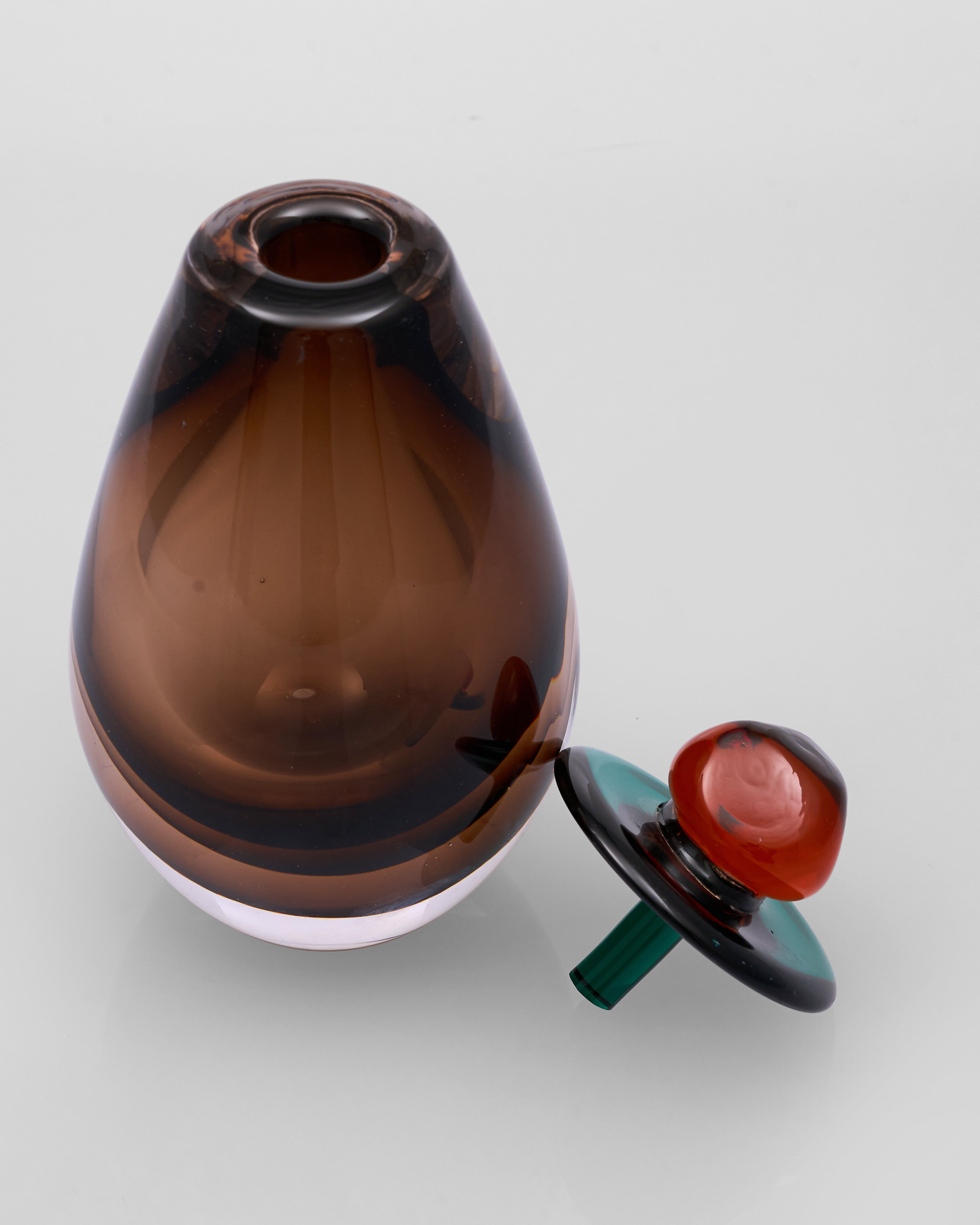 Brown glass vase with a decorative stopper on a light gray background