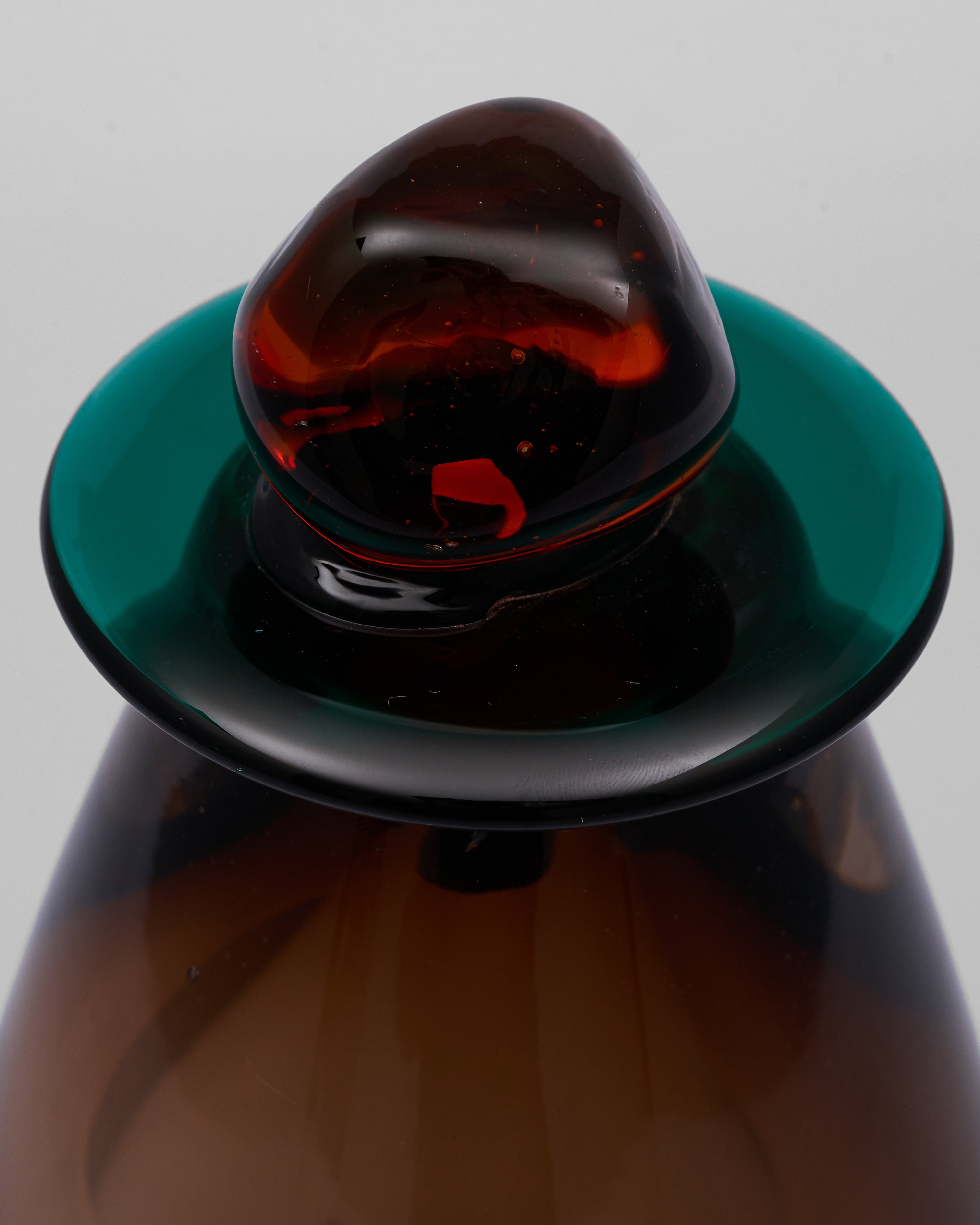 Close-up of a glass bottle with an amber-colored cap on a gray background