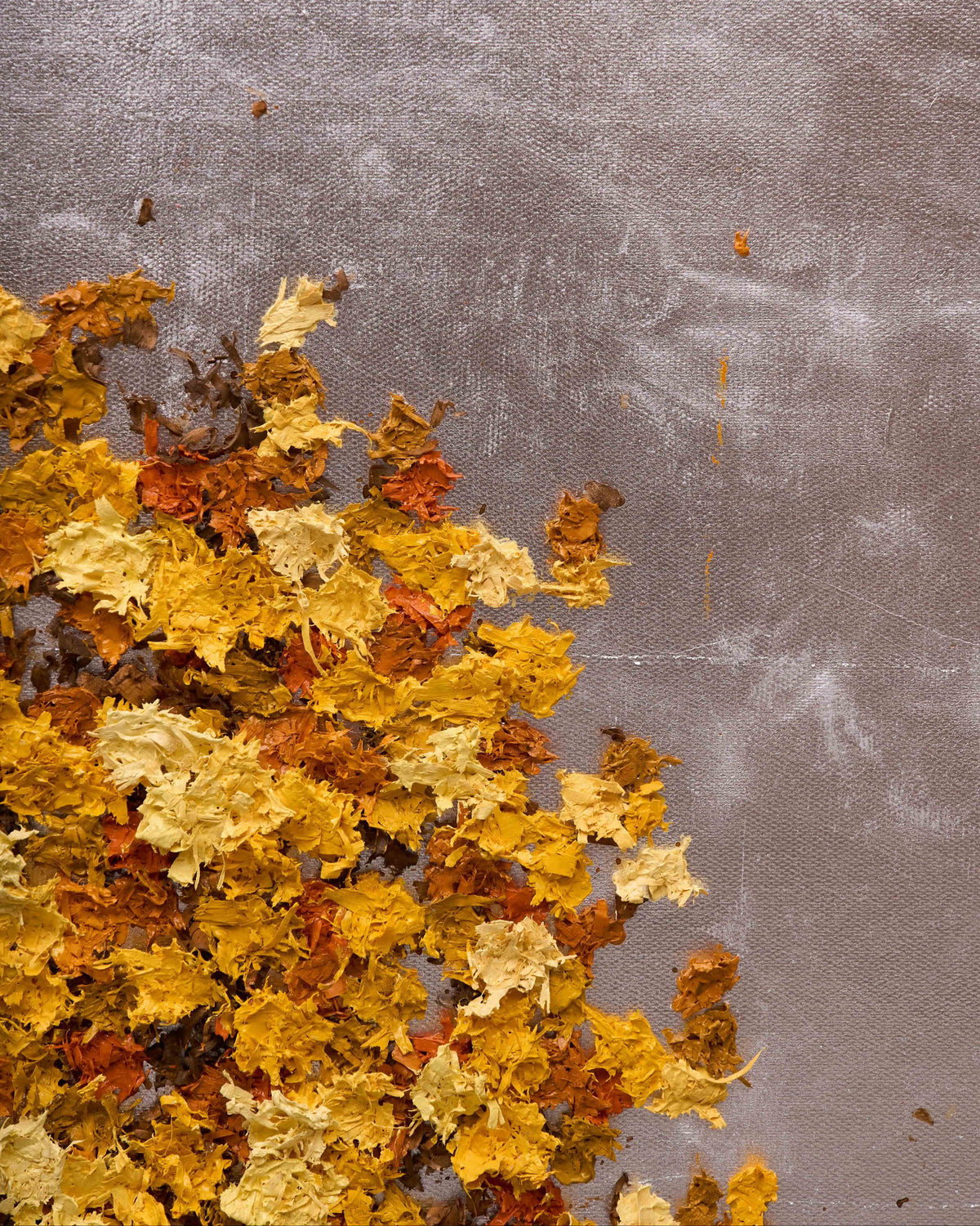 A cluster of textured, hand-painted autumn leaves in shades of yellow, orange, and brown, arranged along the bottom-left corner of a textured gray background.