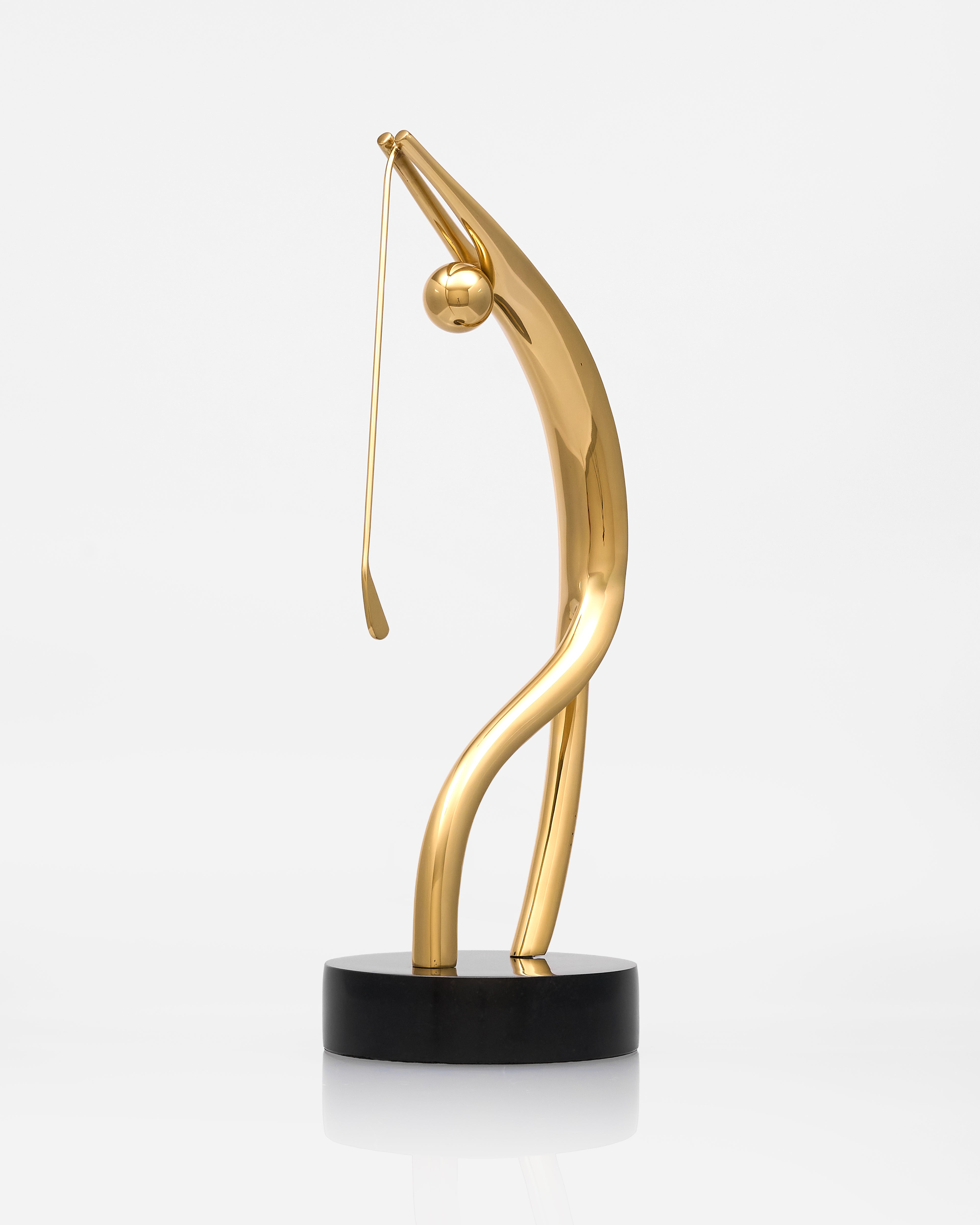Gold sculpture of a figure on a black base against a white background