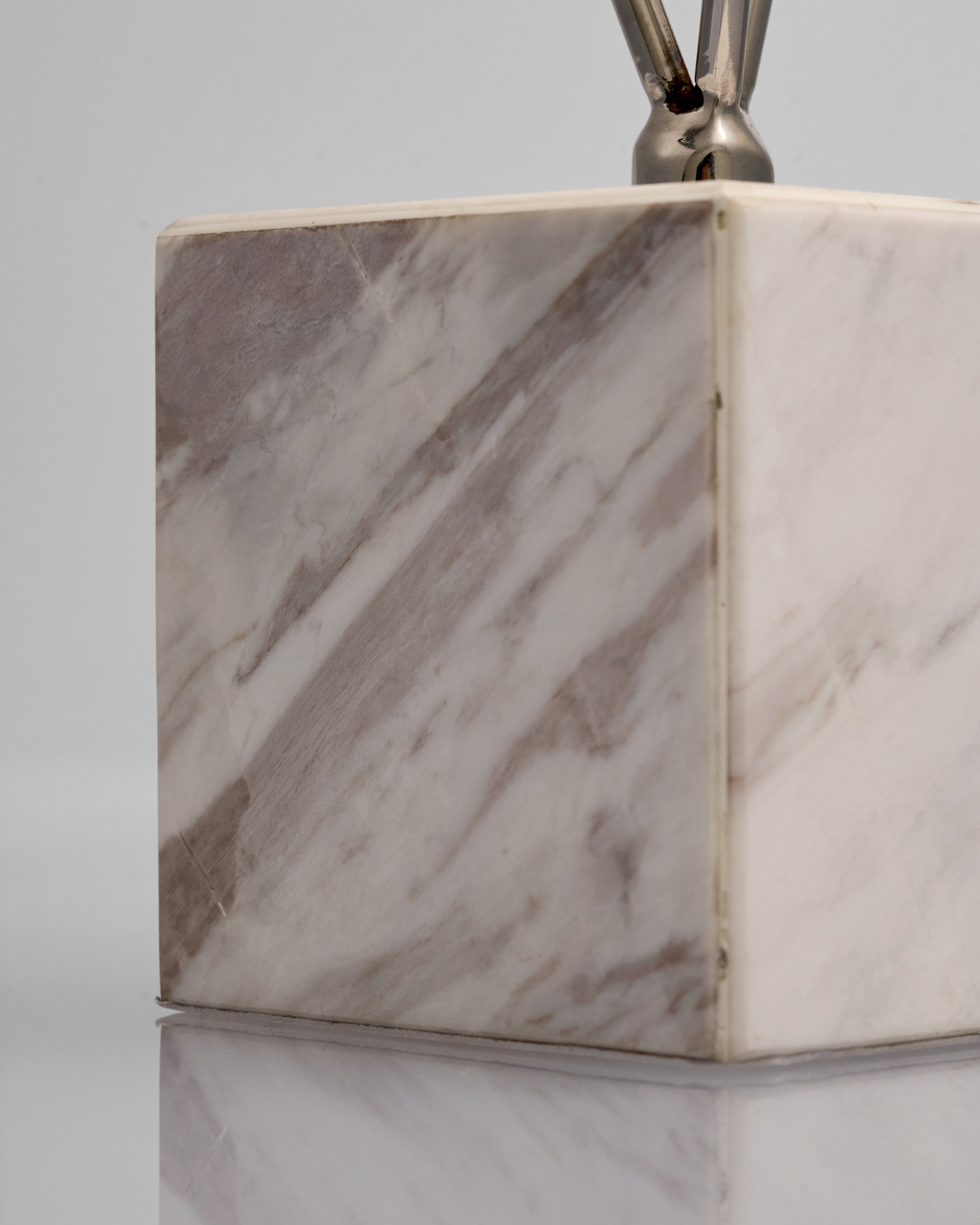 Marble-textured cube with metallic top on a reflective surface