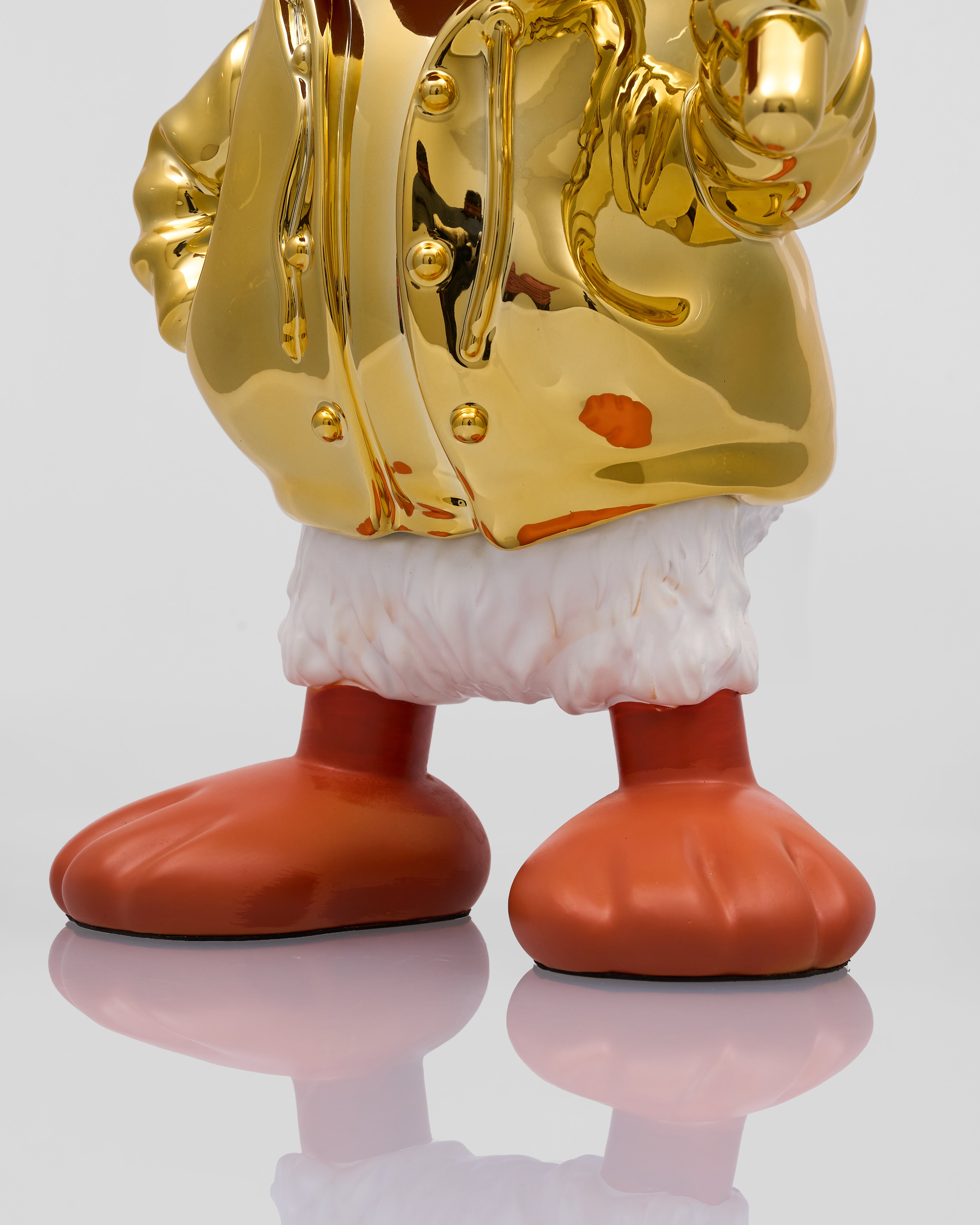 Gold and red character figure on a reflective surface with a light gray background