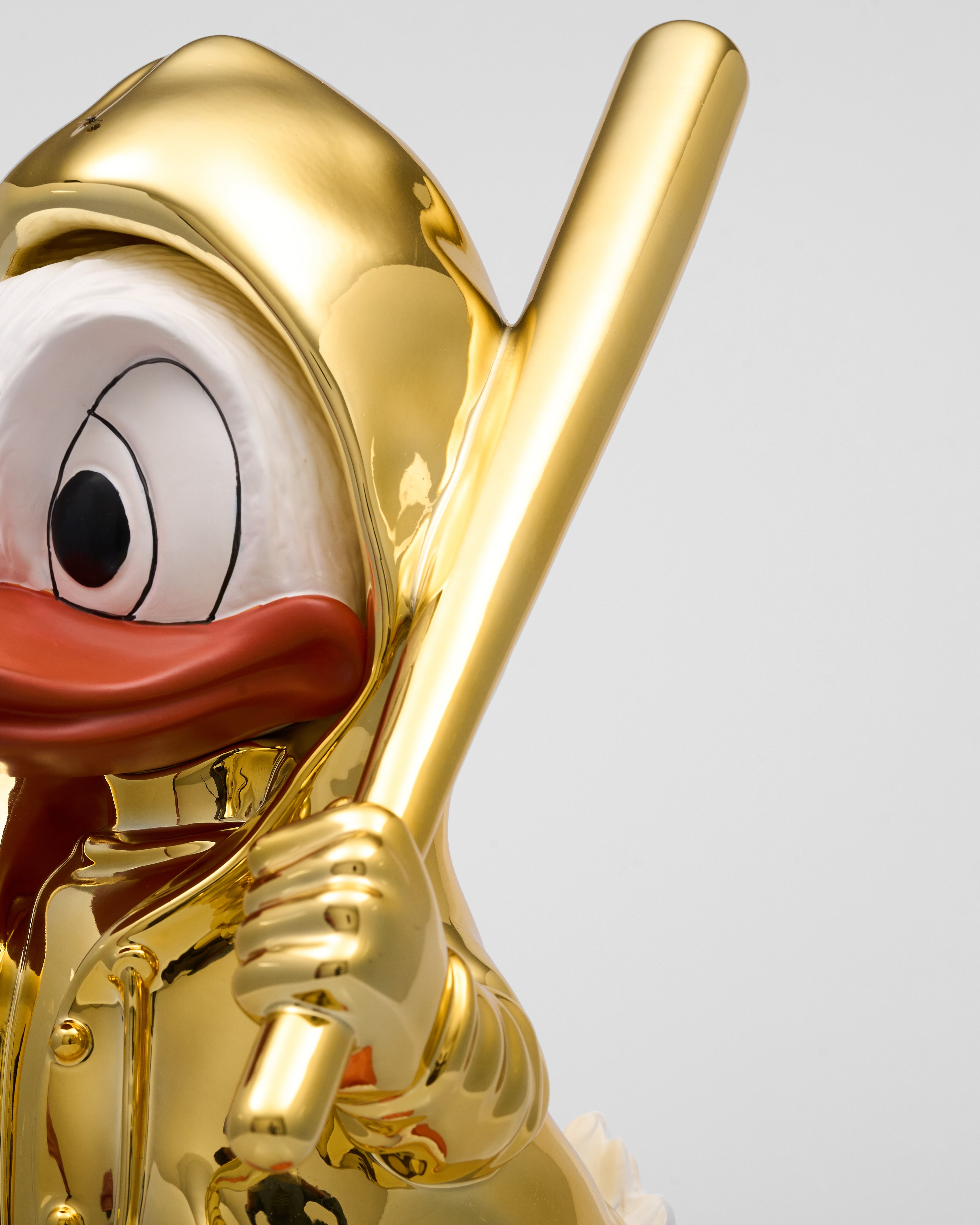 Gold-plated figure of a cartoon duck holding a baseball bat on a light gray background