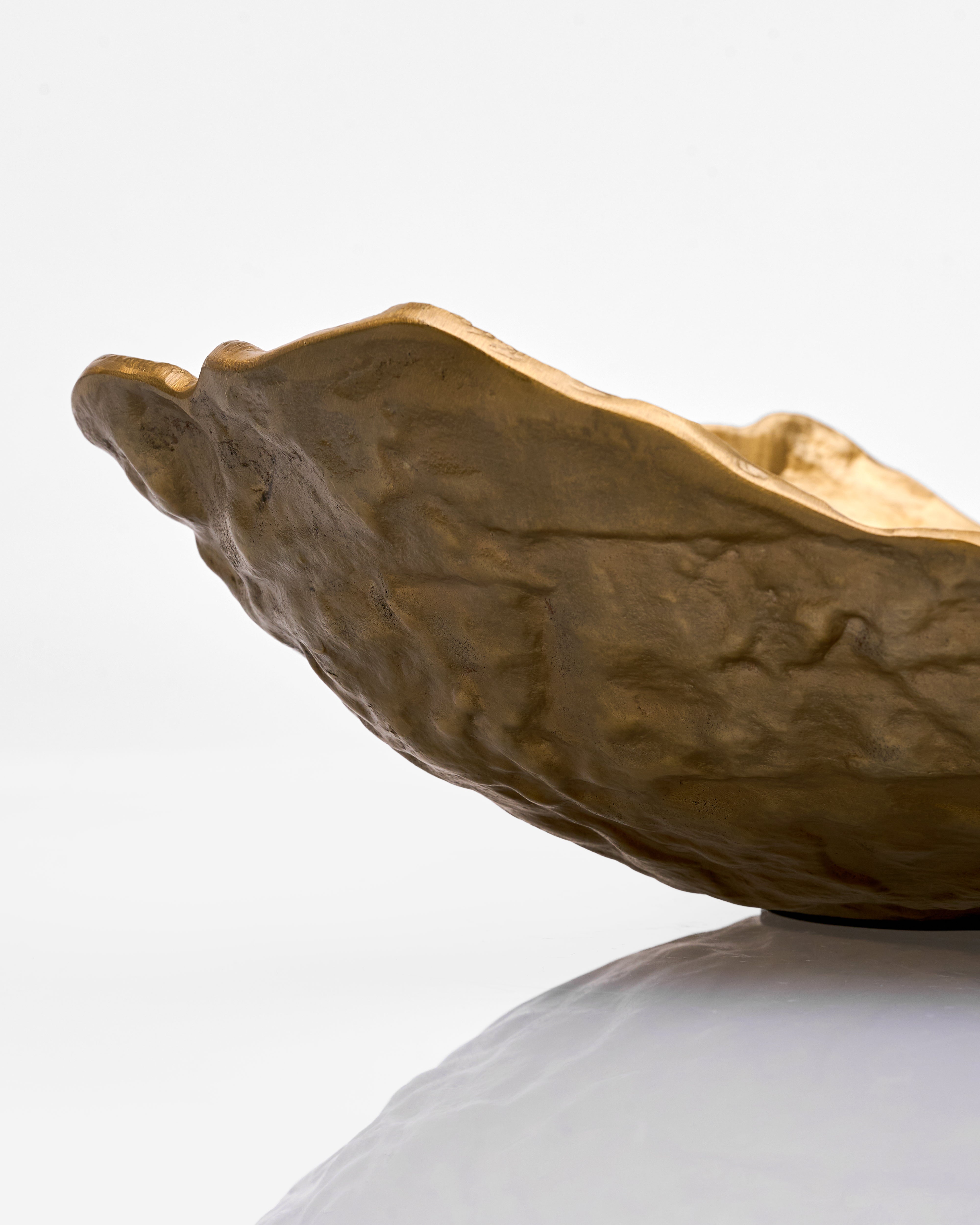 Gold leaf-shaped object on a white surface with a light gray background