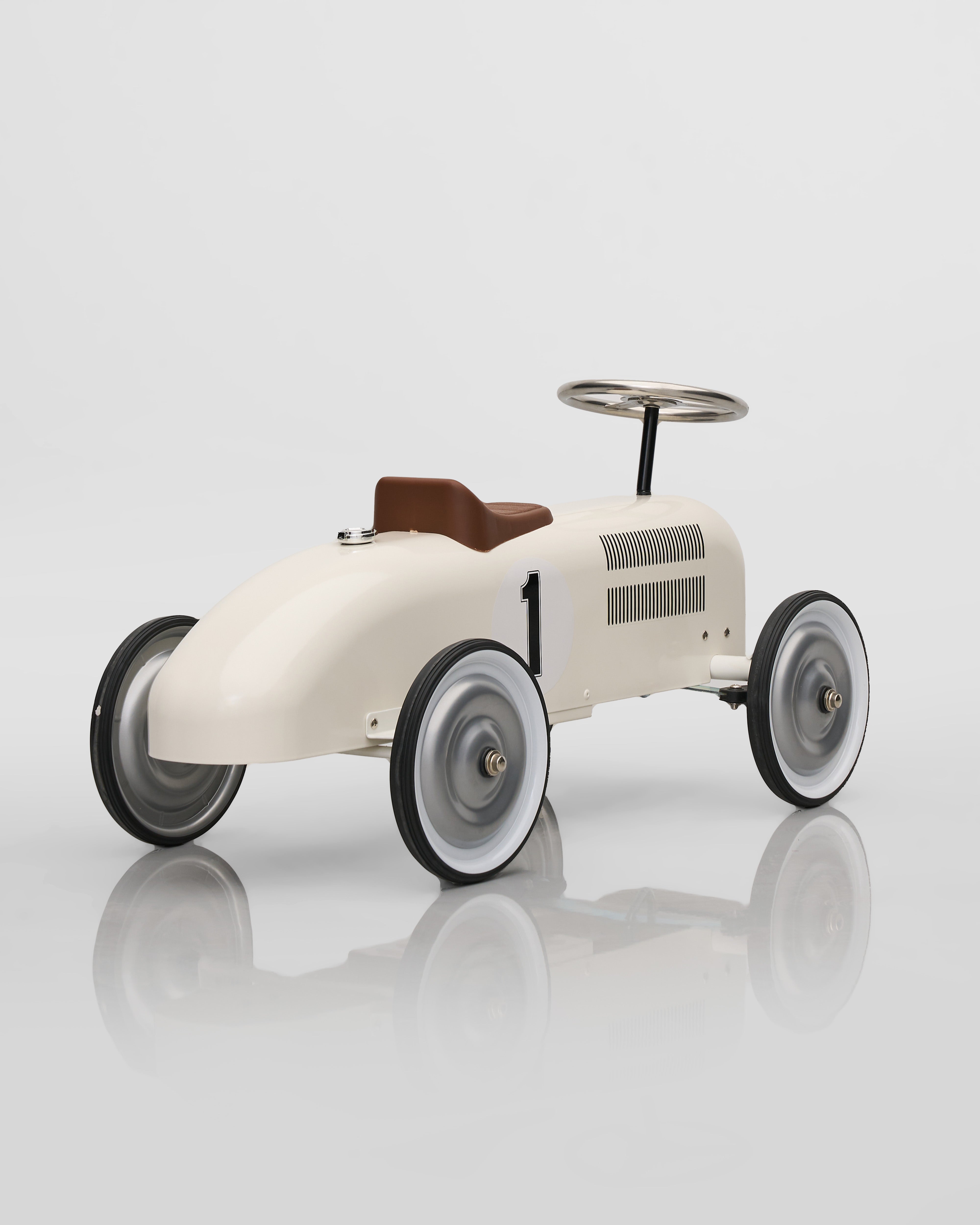 Vintage-style toy car on a reflective surface with a white background