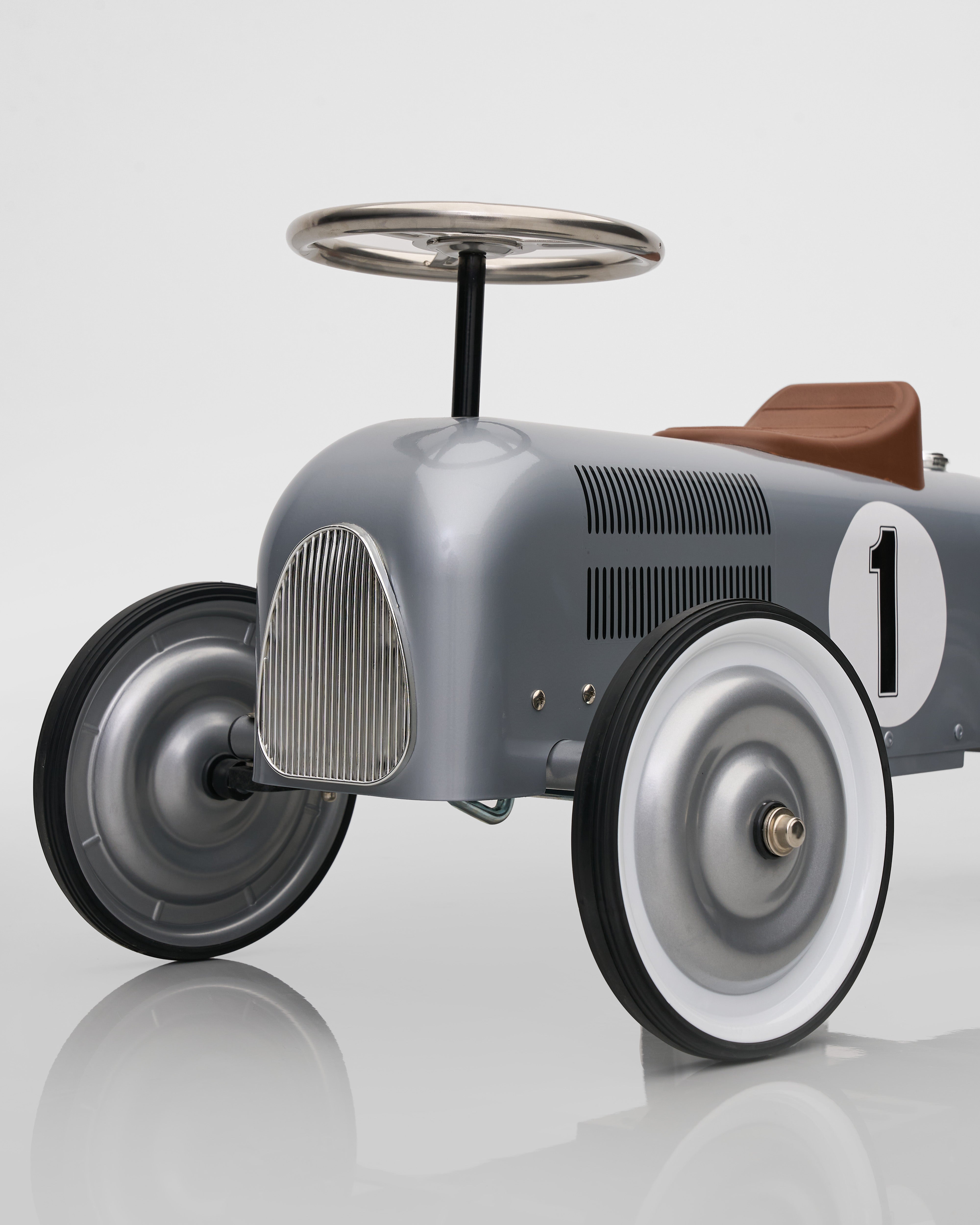 Vintage-style toy car with a steering wheel on a reflective surface