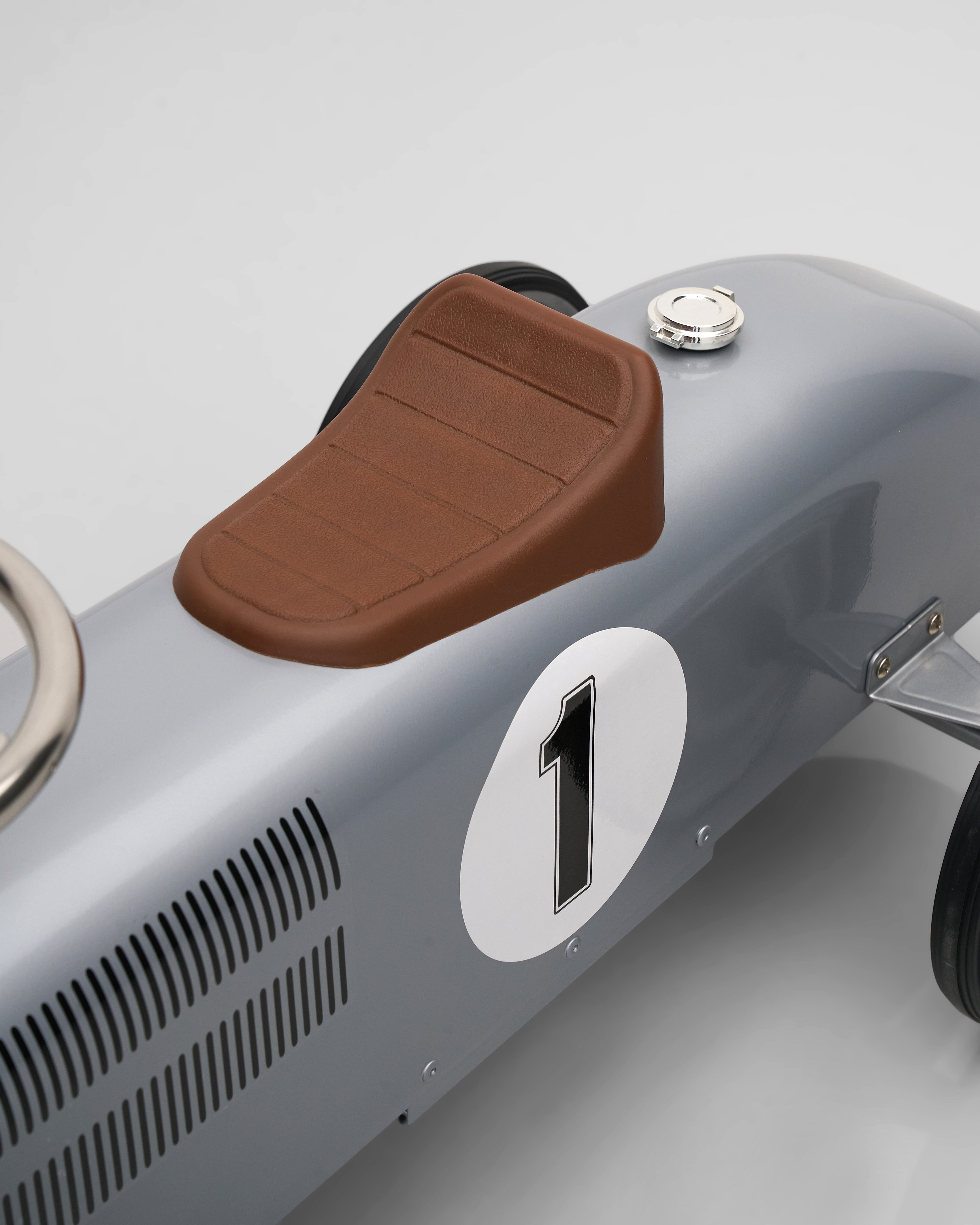 Close-up of a vintage-style car with a brown seat and number 1 on a gray background