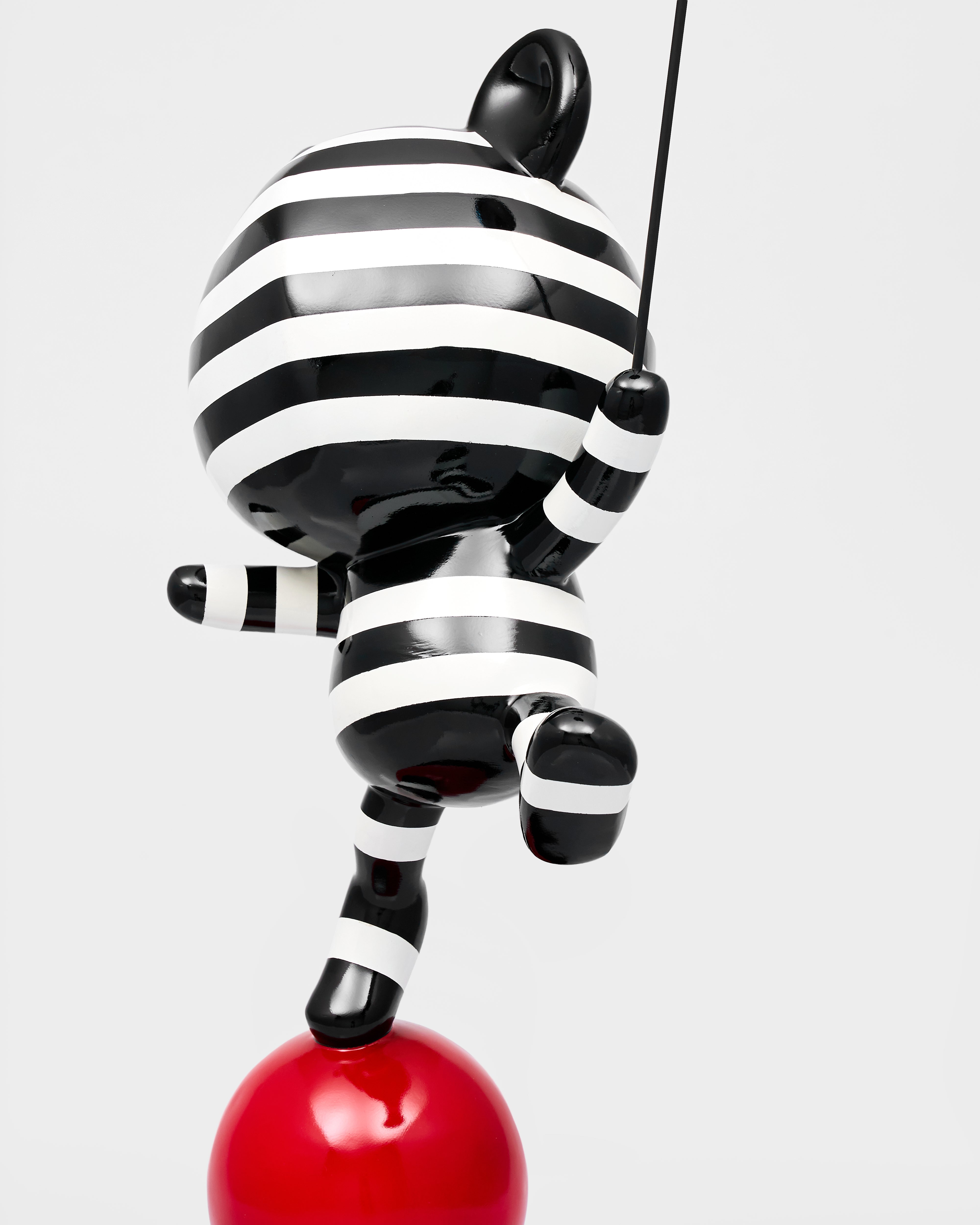 Black and white striped cat toy on a red ball against a white background